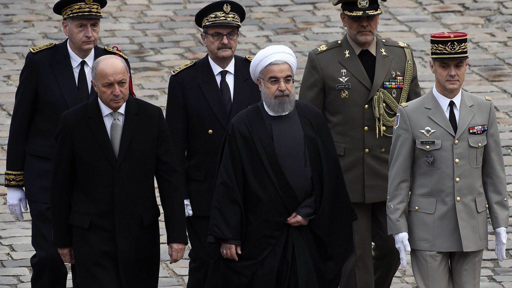 French Foreign Minister Laurent Fabius (2nd L) greets Iranian President Hassan Rouhani (C) during a welcoming ceremony on January 28, 2016 at the Invalides in Paris