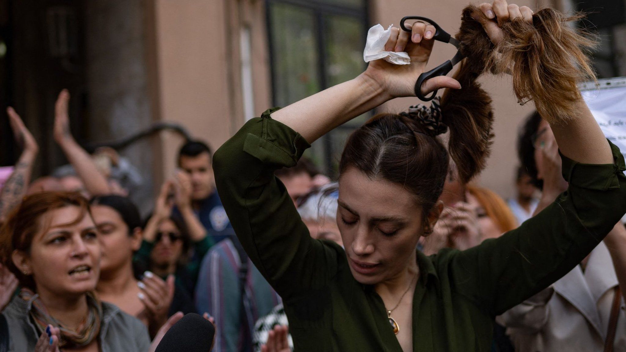 Nasibe Samsaei, an Iranian woman living in Turkey, holds up her hair after cutting it off with a pair of scissors, during a protest on September 21, 2022