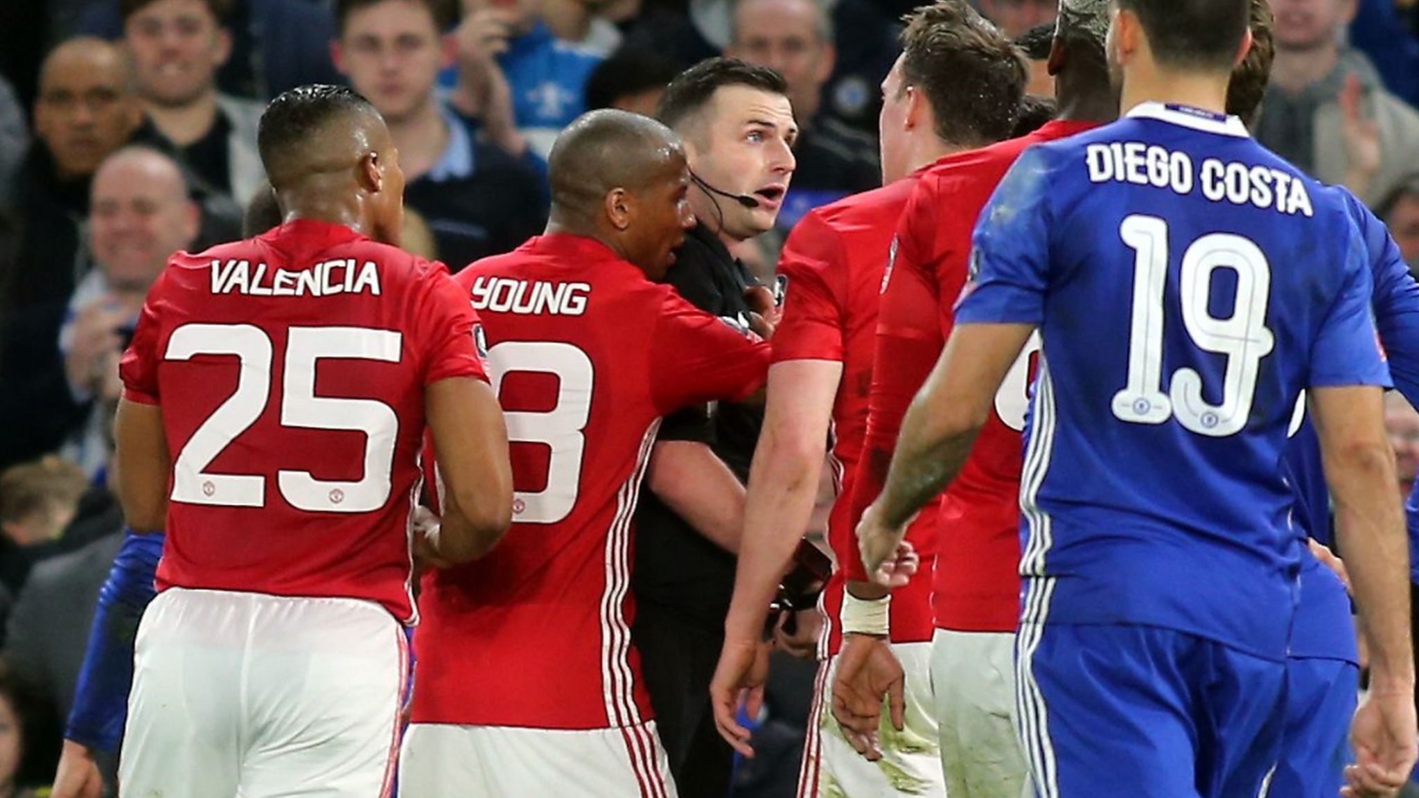 Referee Michael Oliver is surrounded by several Manchester United players after sending off midfielder Ander Herrera