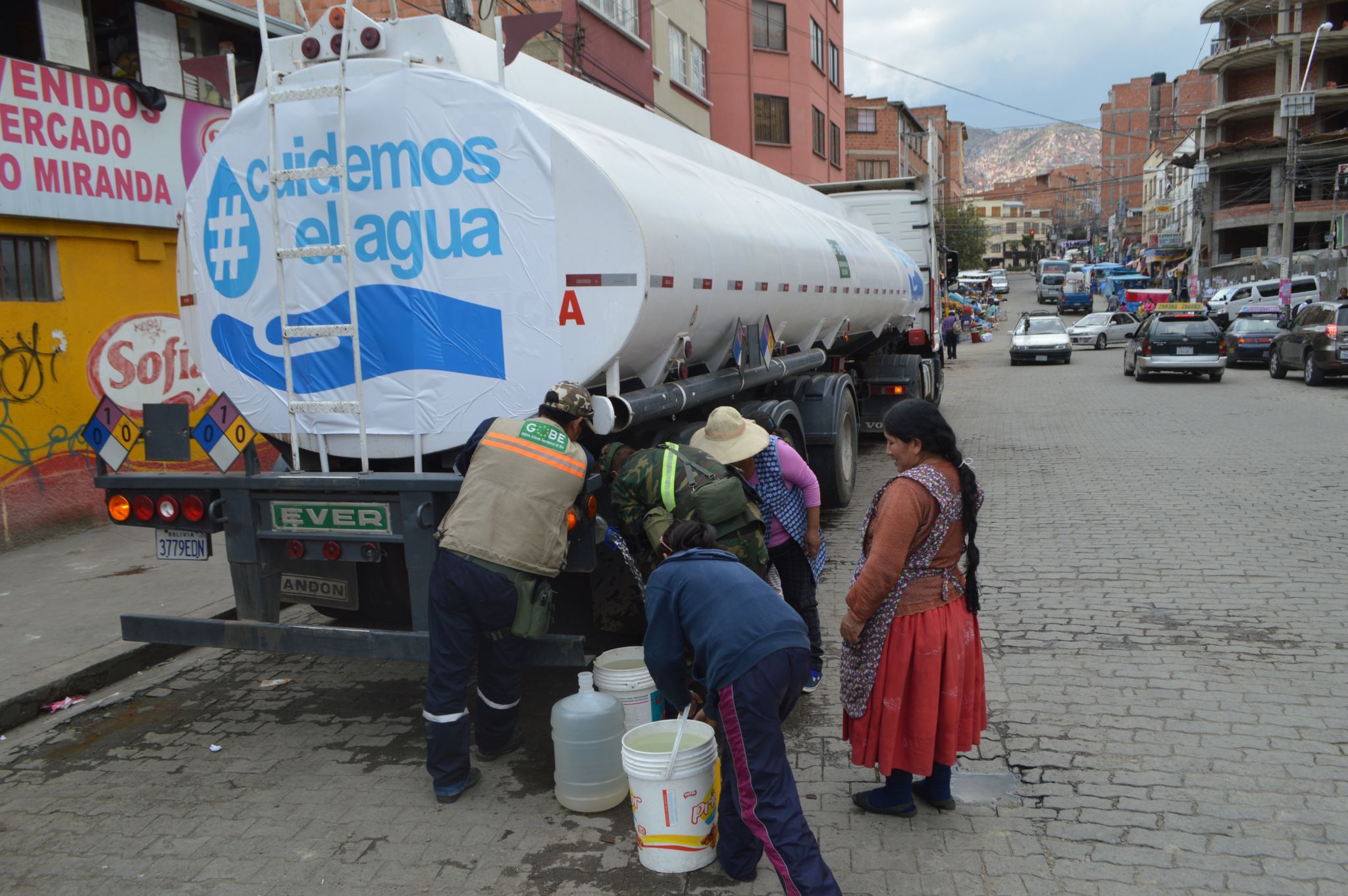 People in La Paz stand next to a lorry delivering water
