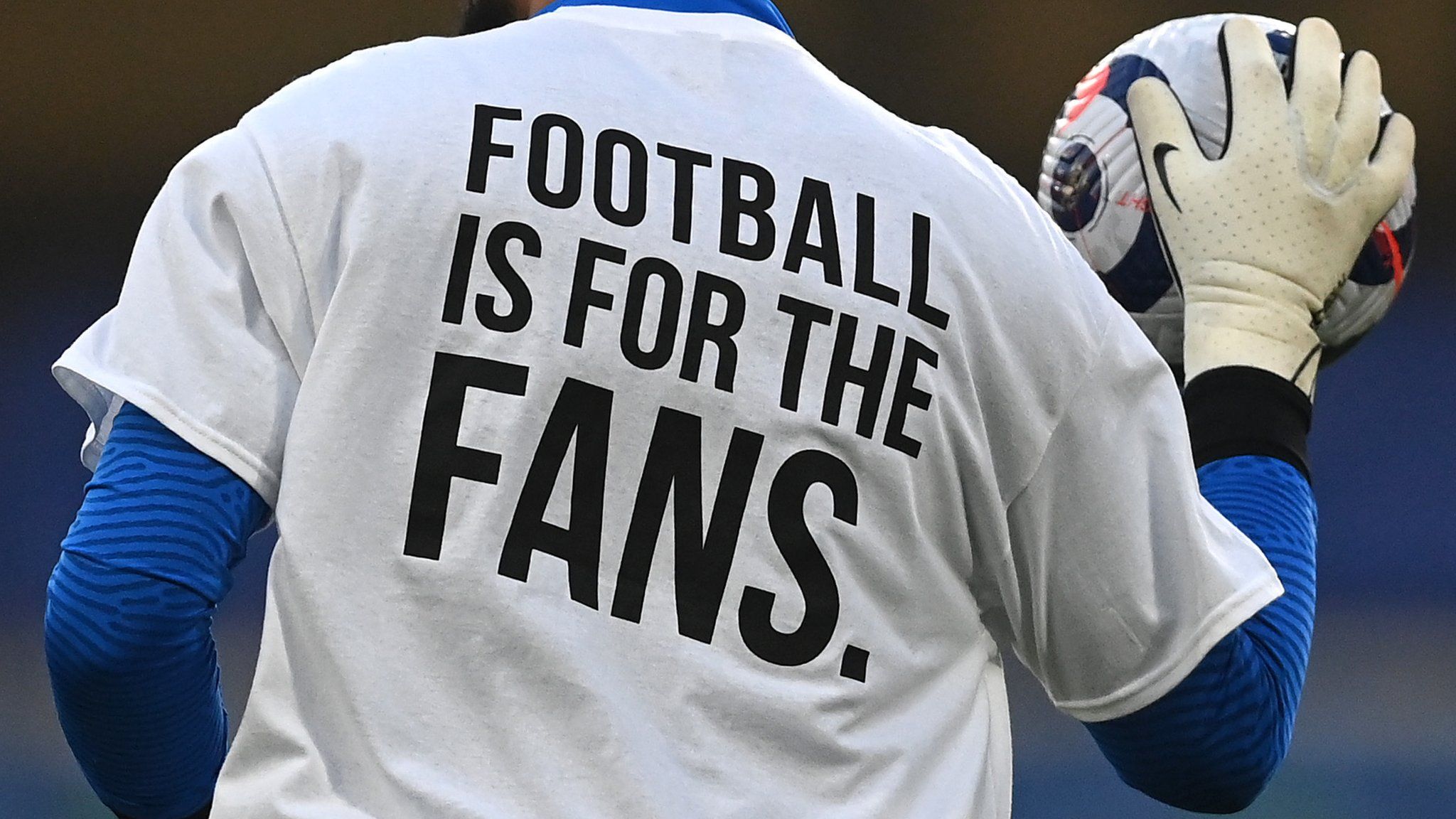 A Brighton player wears a t-shirt with the slogan 'Football is for the fans' on the back in protest against the proposed European Super League before a match against Chelsea