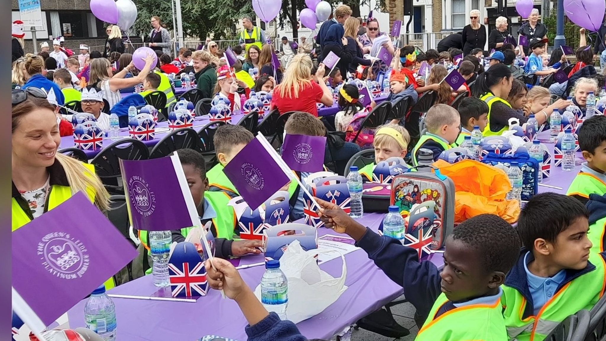 Schoolchildren wave flags at a jubilee street party