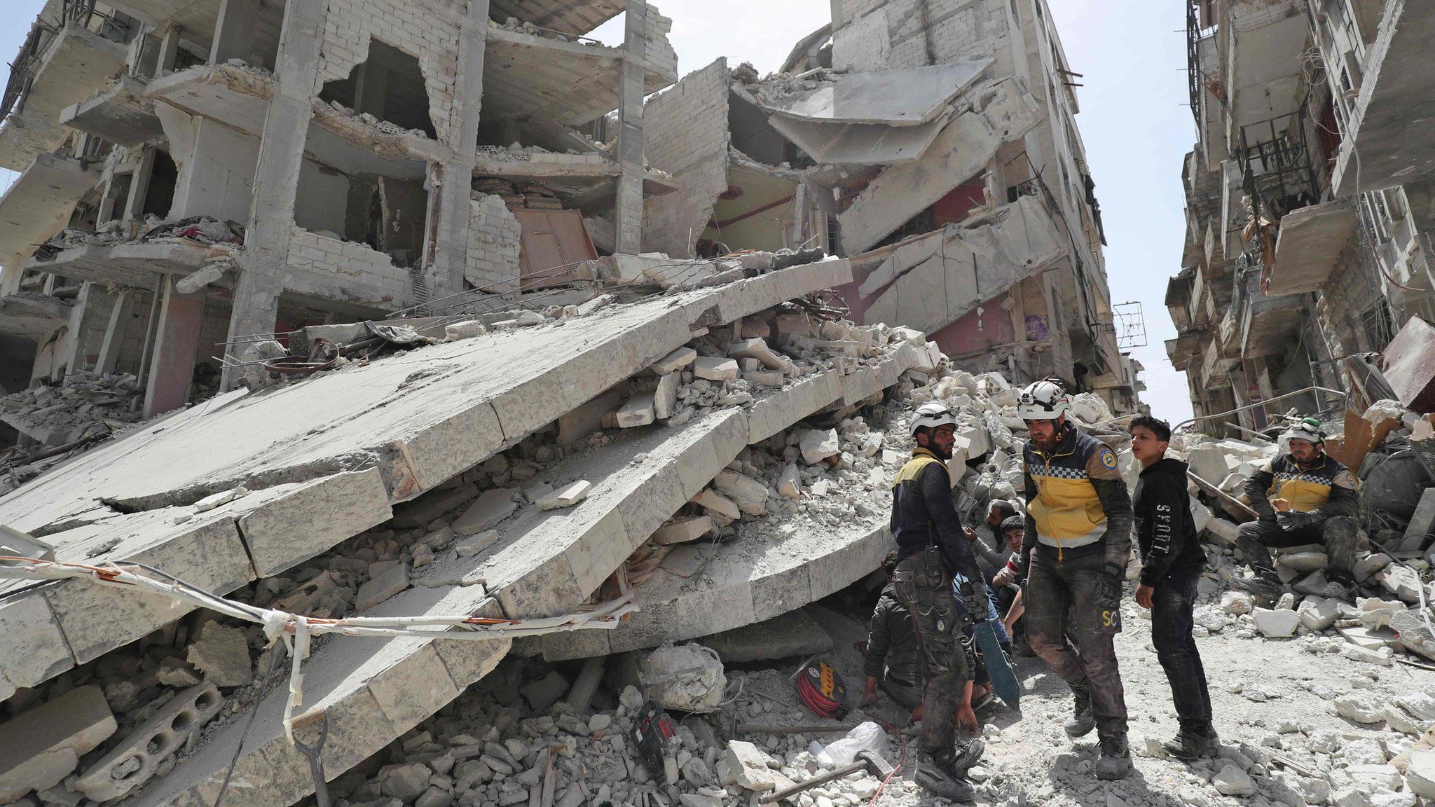 Rescue workers from the Syria Civil Defence, also known as the White Helmets, search the rubble of a collapsed building following an explosion in the opposition-held town of Jisr al-Shughour (24 April 2019)