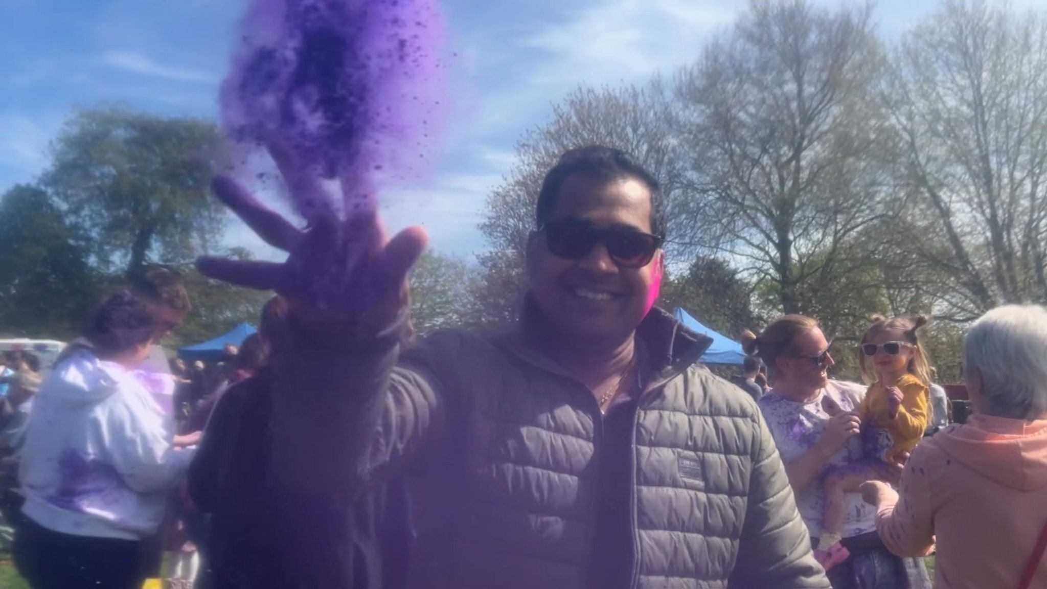A man throws purple powder at the camera