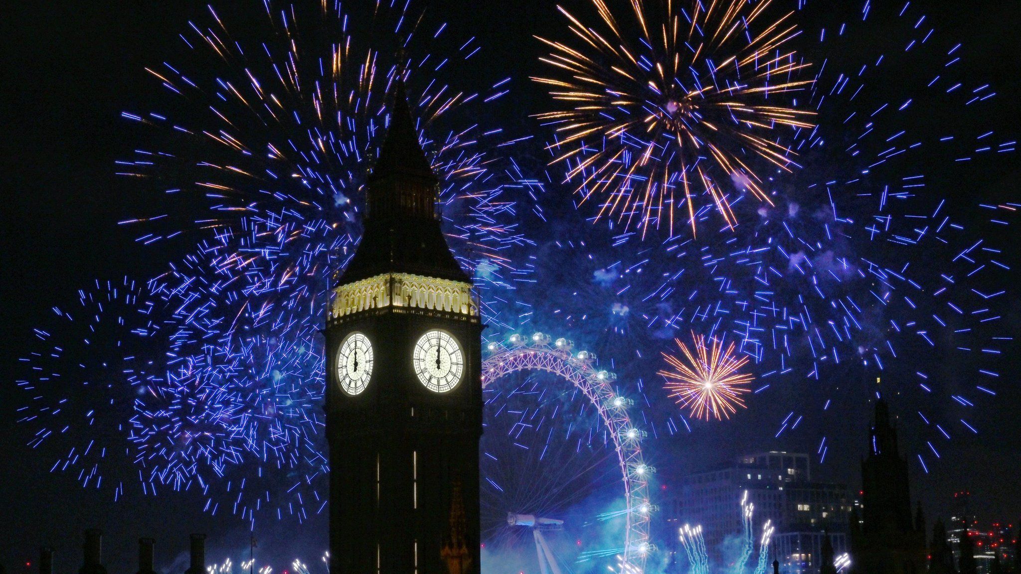 Fireworks light up the sky over Elizabeth Tower, also known as Big Ben and the London Eye in central London during the New Year celebrations