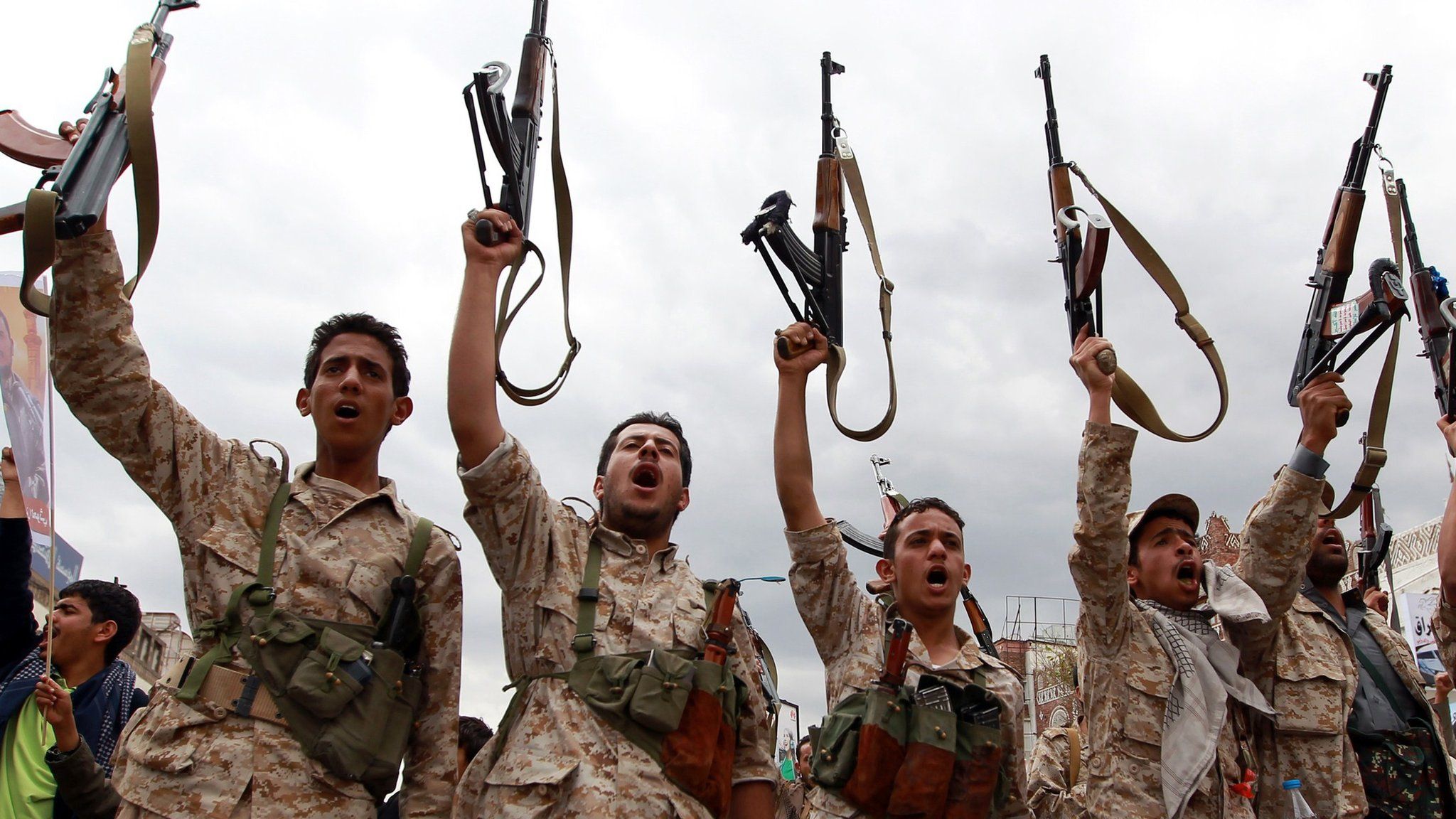 Yemeni men wearing military fatigue and loyal to the Houthi movement brandish their weapons