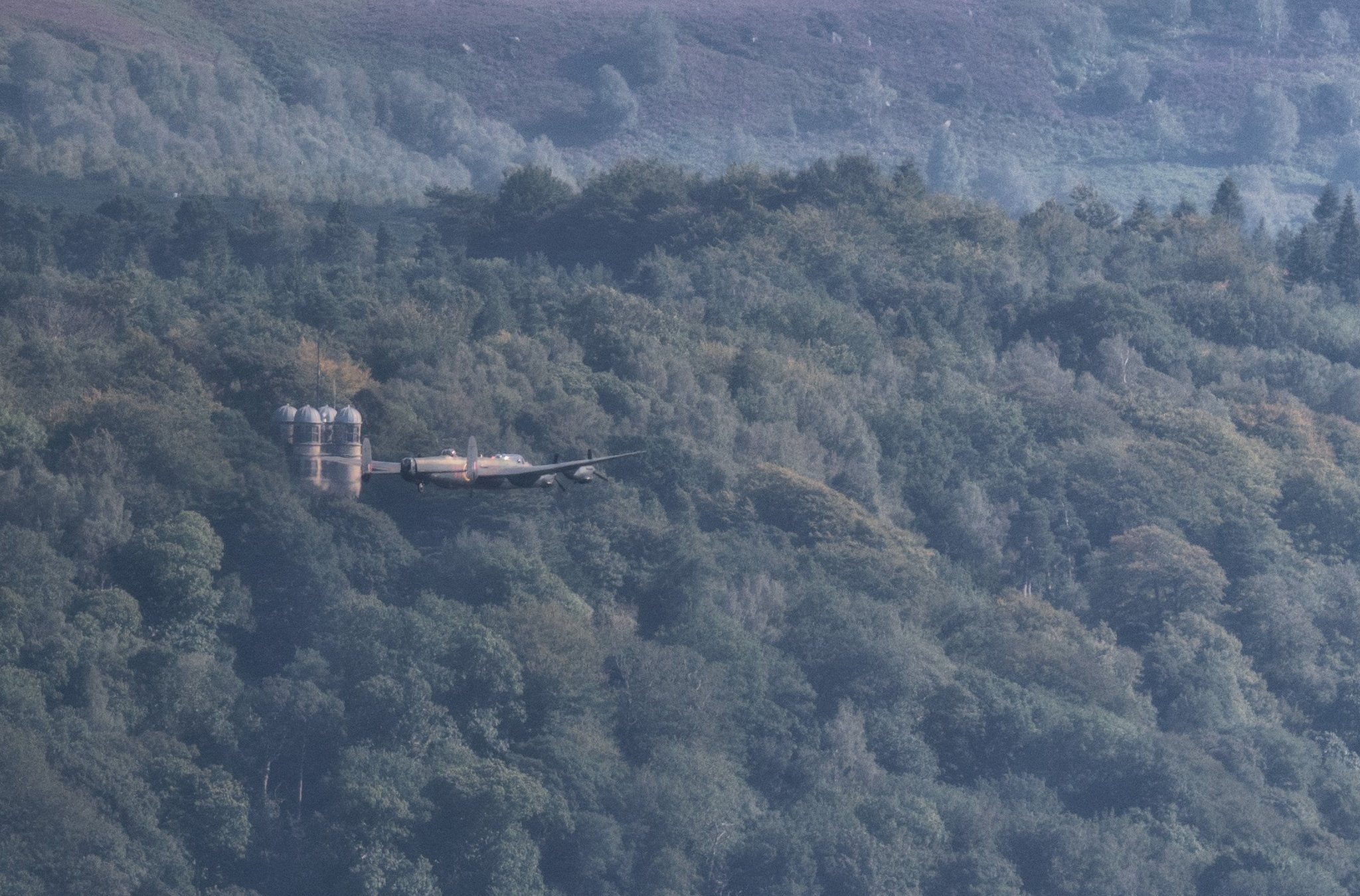 Lancaster Bomber flying past the hunting tower at Chatsworth House, in Derbyshire