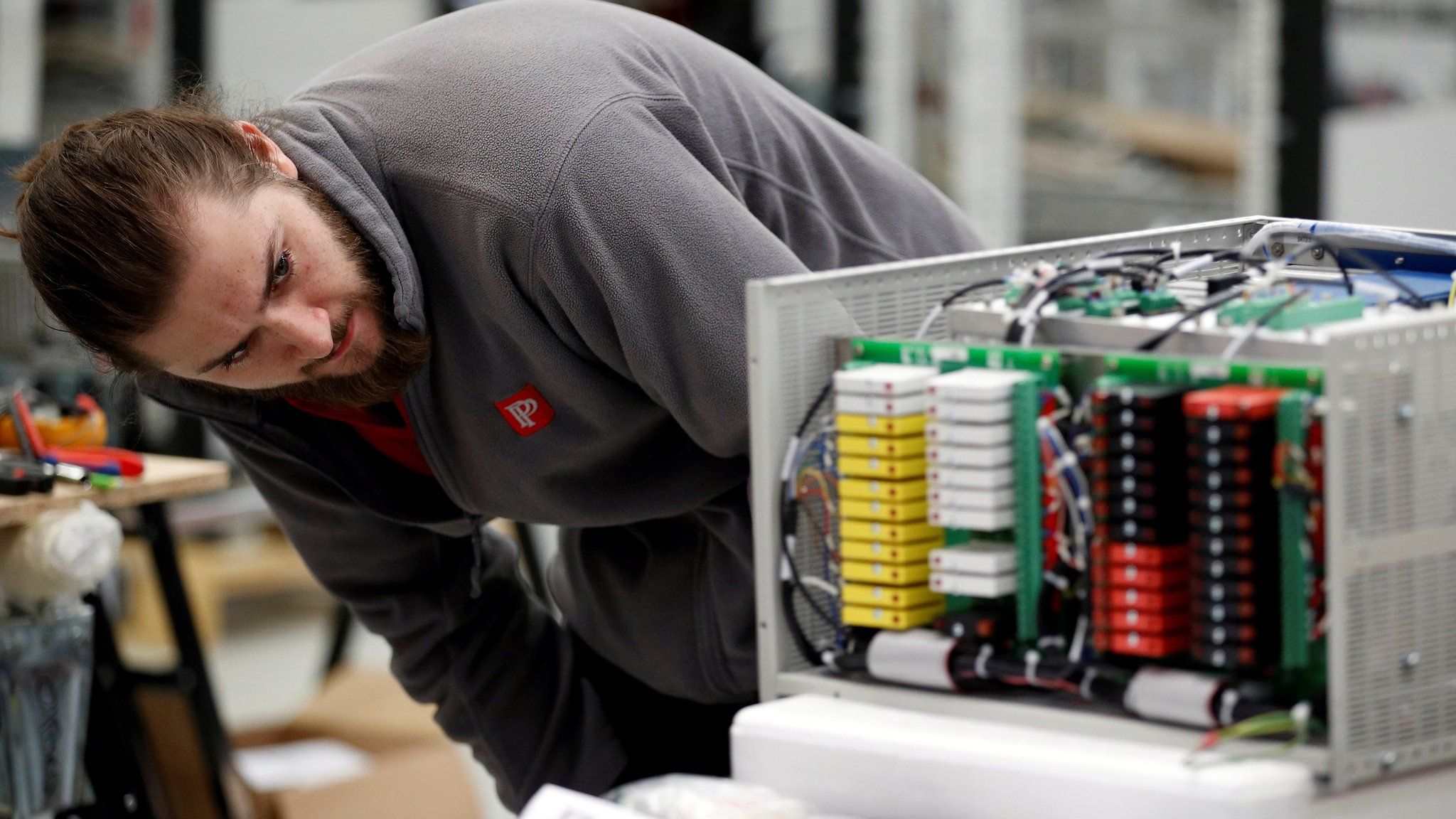 A worker examines an electrical component on the factory floor of PP Control and Automation near Cannock