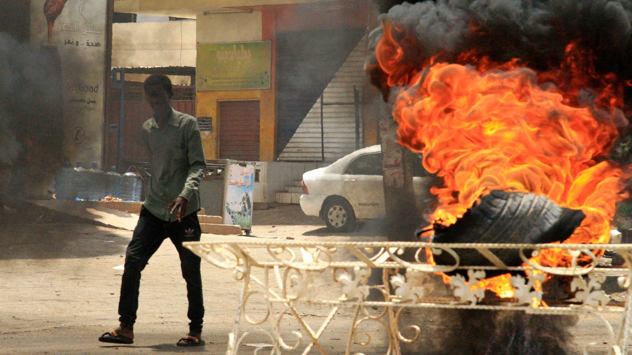 A Sudanese protester walks past a burning tyre near Khartoum's army headquarters