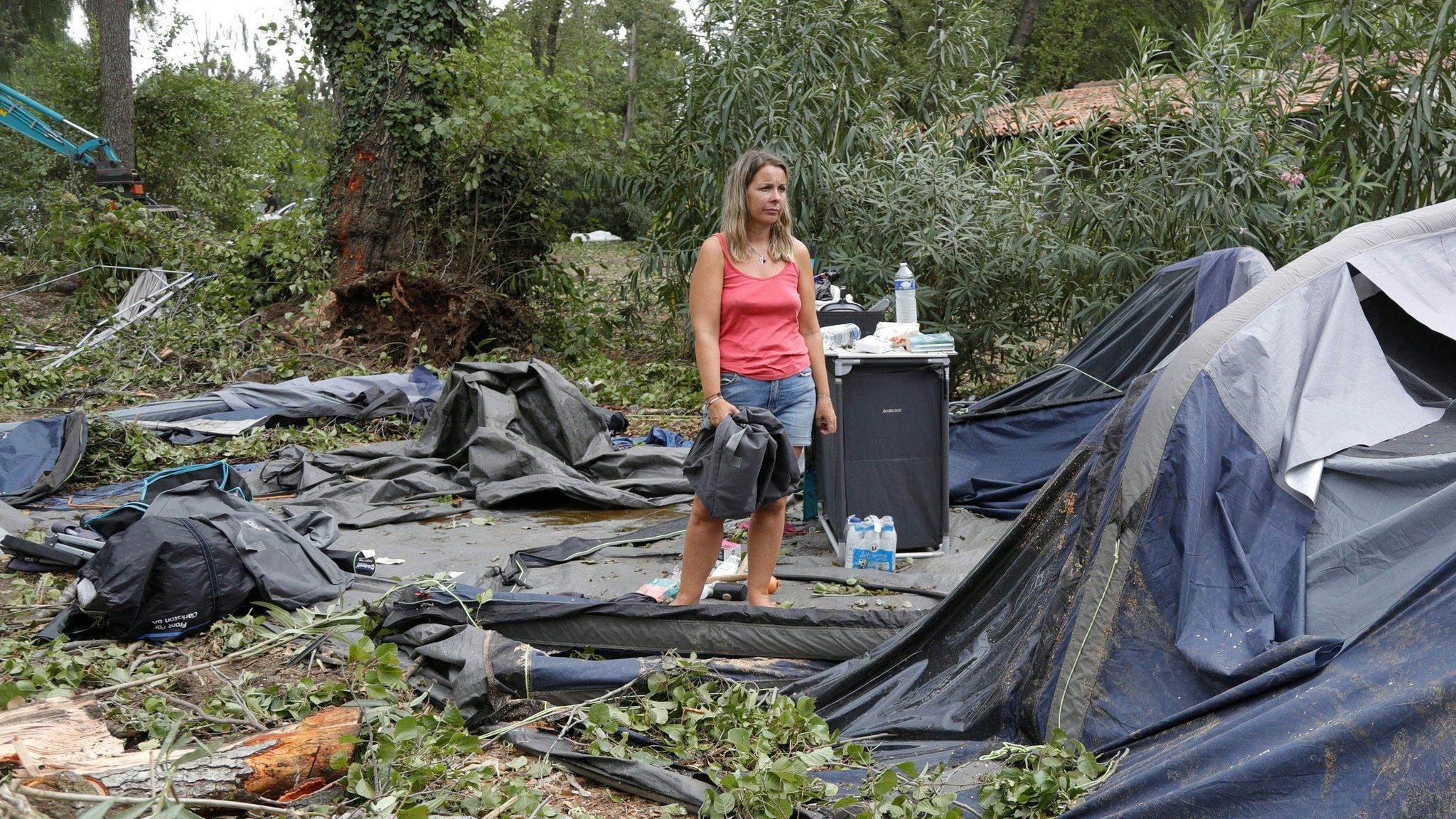 A woman stands in the wreckage of a tent