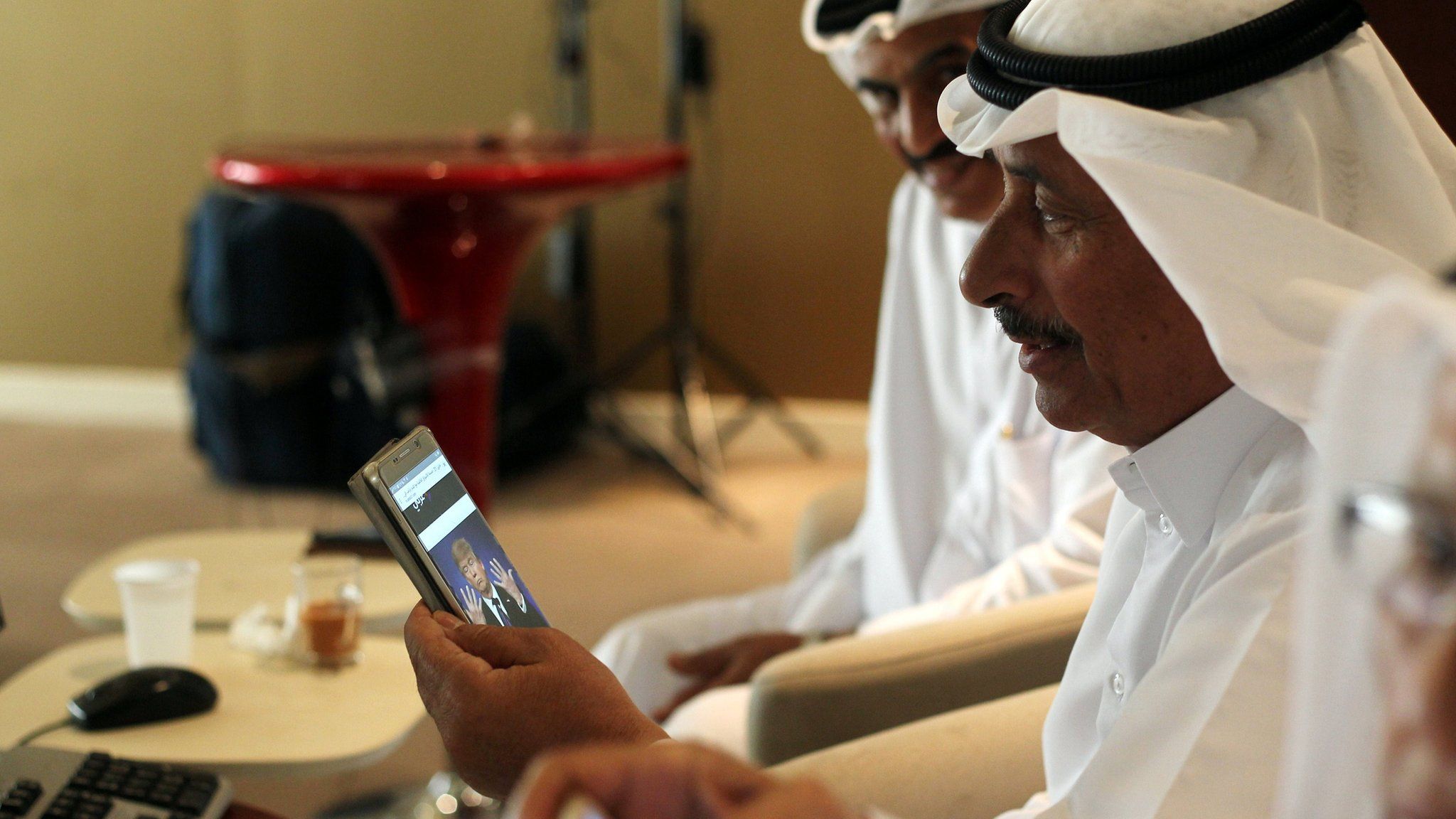 File photo showing a trader using his phone to follow news of the US presidential election result in Doha, Qatar (9 November 2016)