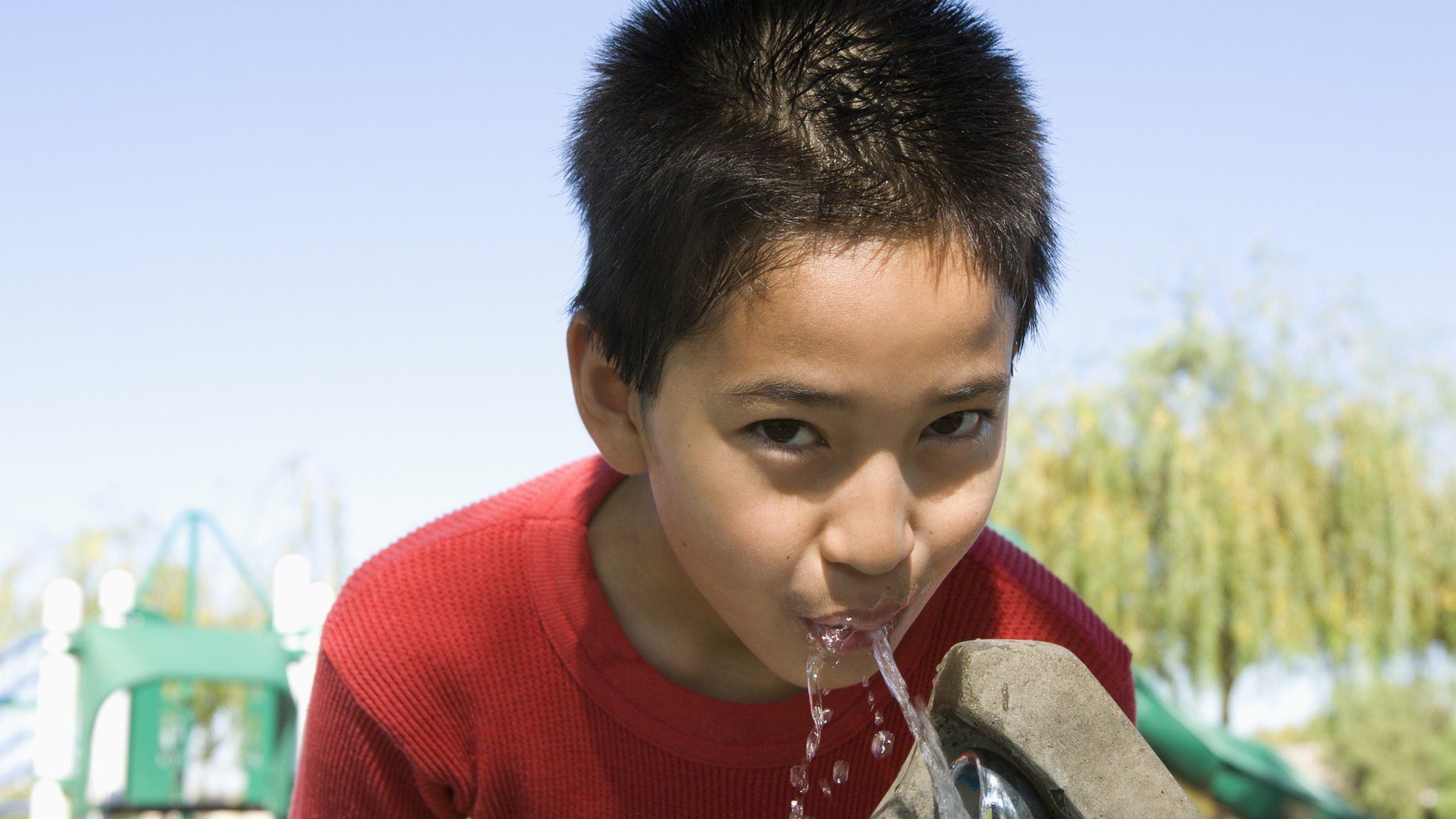 Boy drinking at a water fountain