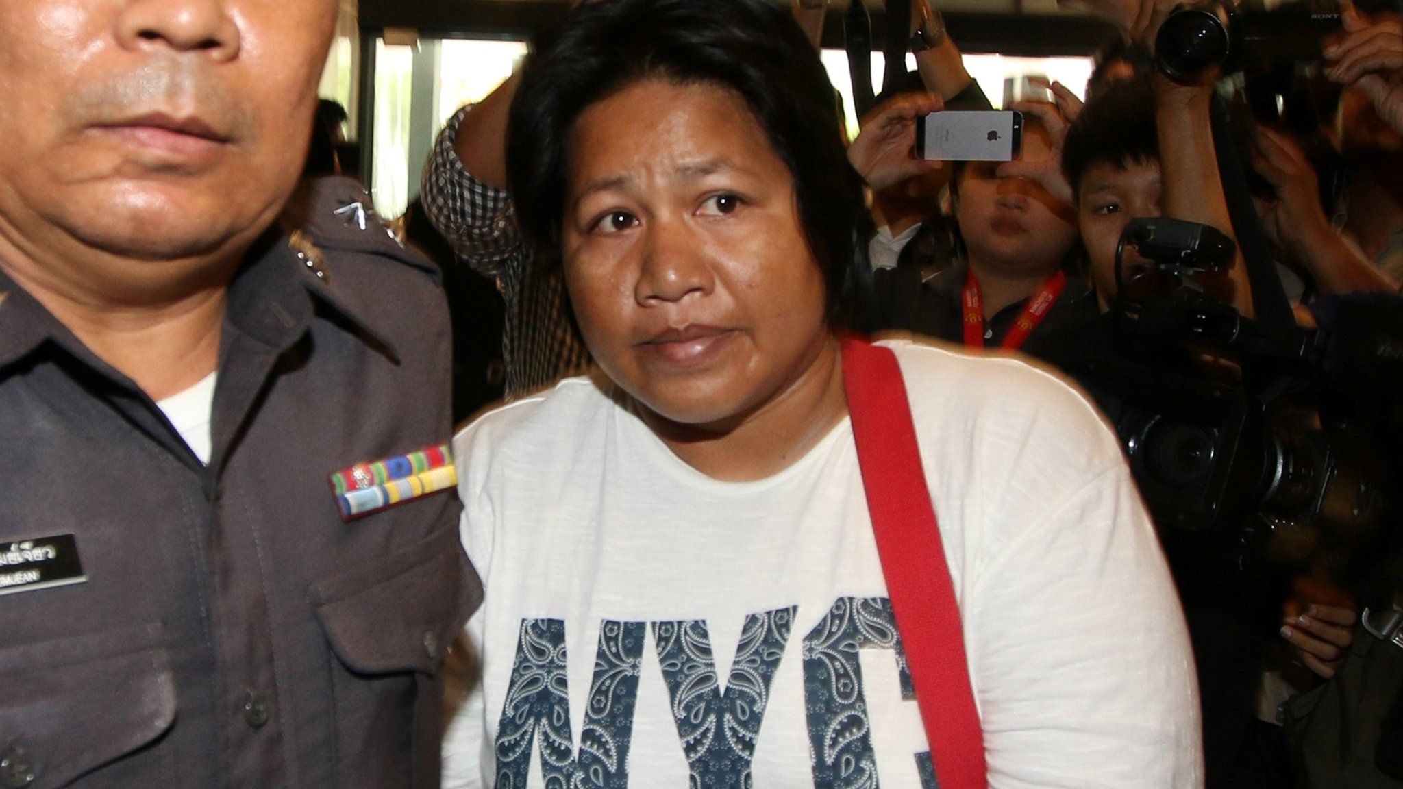 Patnaree Chankij, the mother of an anti-junta activist, is escorted by police as she arrives at a military court in Bangkok, Thailand