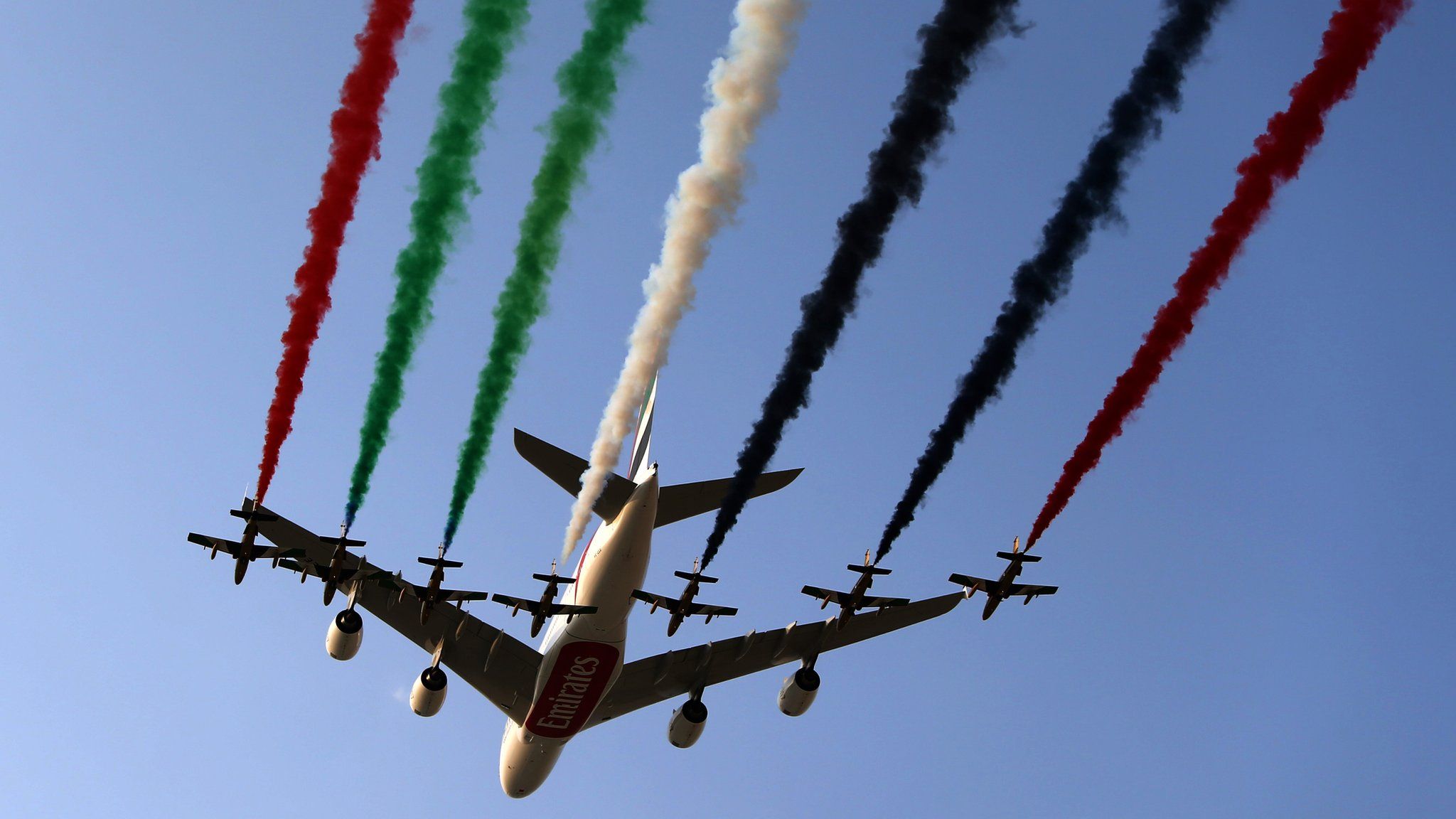 UAE air force aerobatics team performs with an Emirates Airline Airbus A380 at 2013 Dubai Airshow