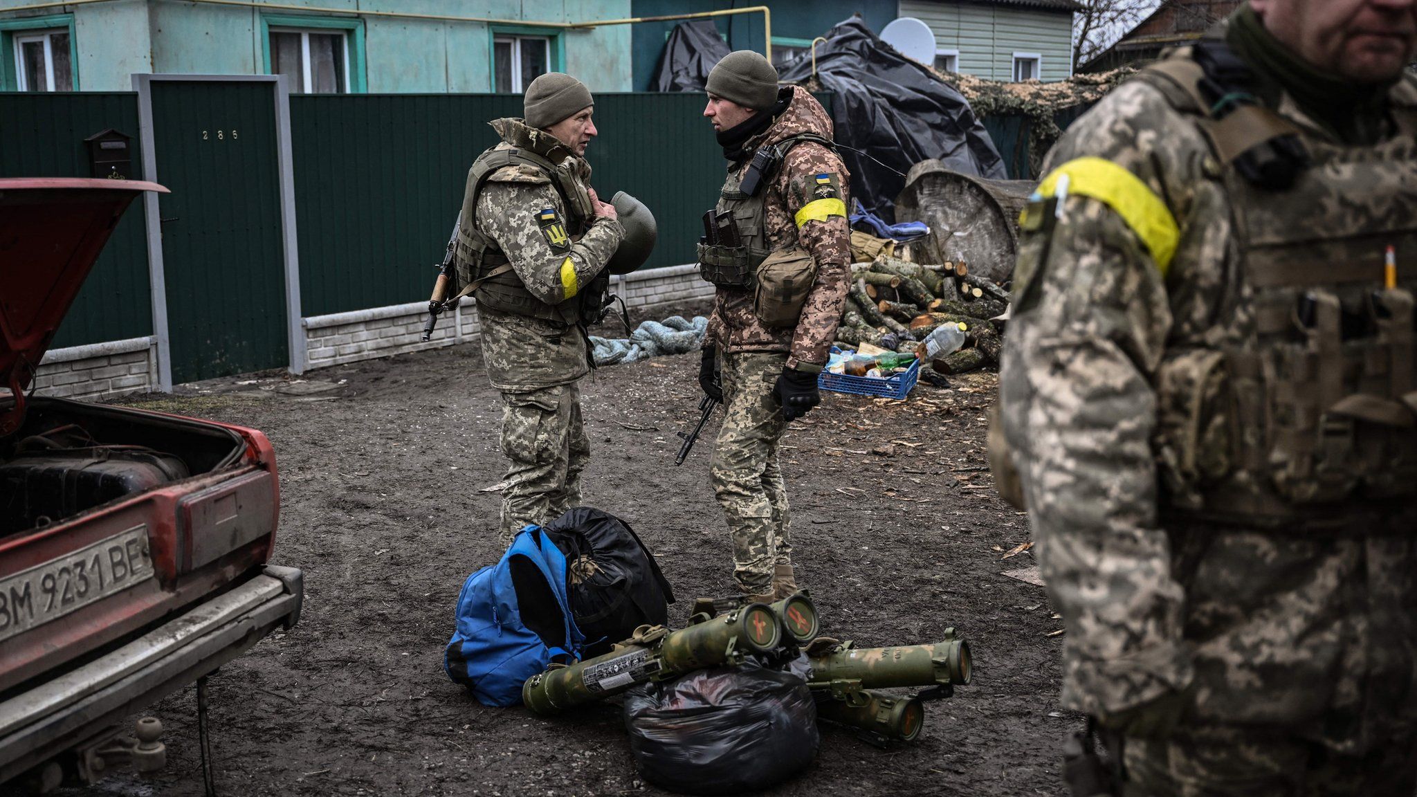 Ukrainian soldiers talk as they stand near their weapons at a frontline, northeast of Kyiv on March 3, 2022.
