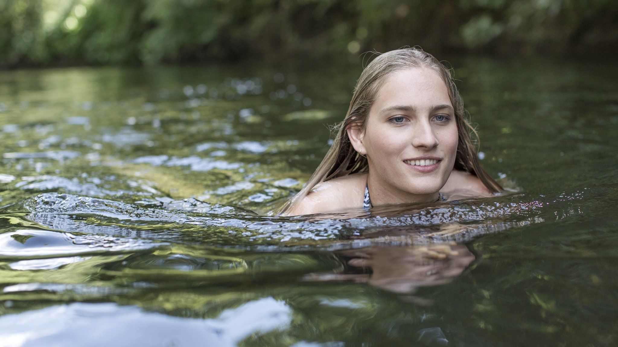 Woman wild swimming in a river