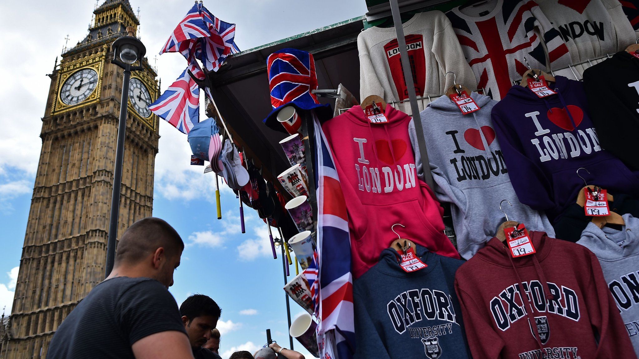 Tourists look at London themed merchandise with Big Ben in background