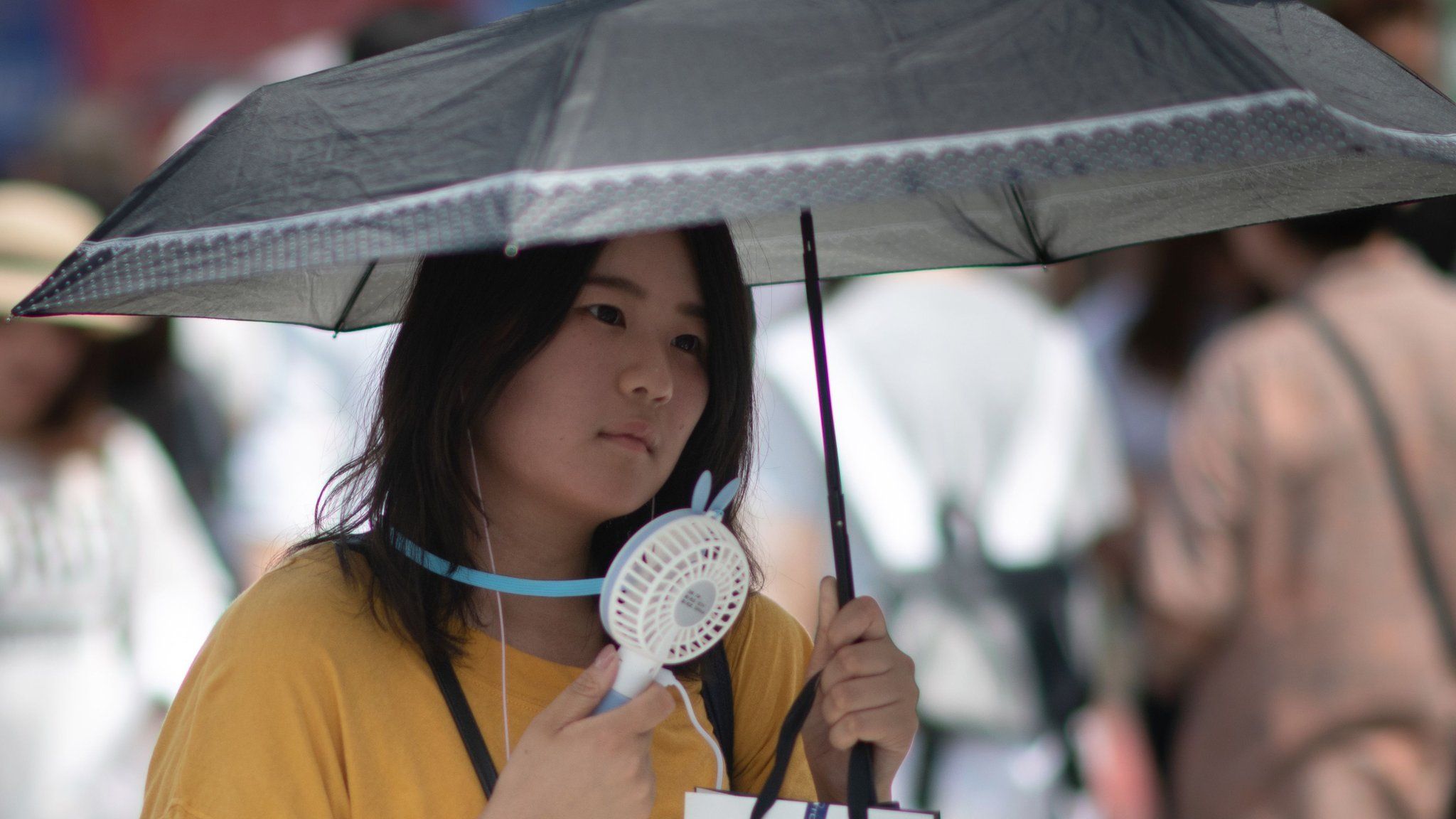 A woman uses a portable fan to cool herself in Tokyo as Japan suffers from a heatwave