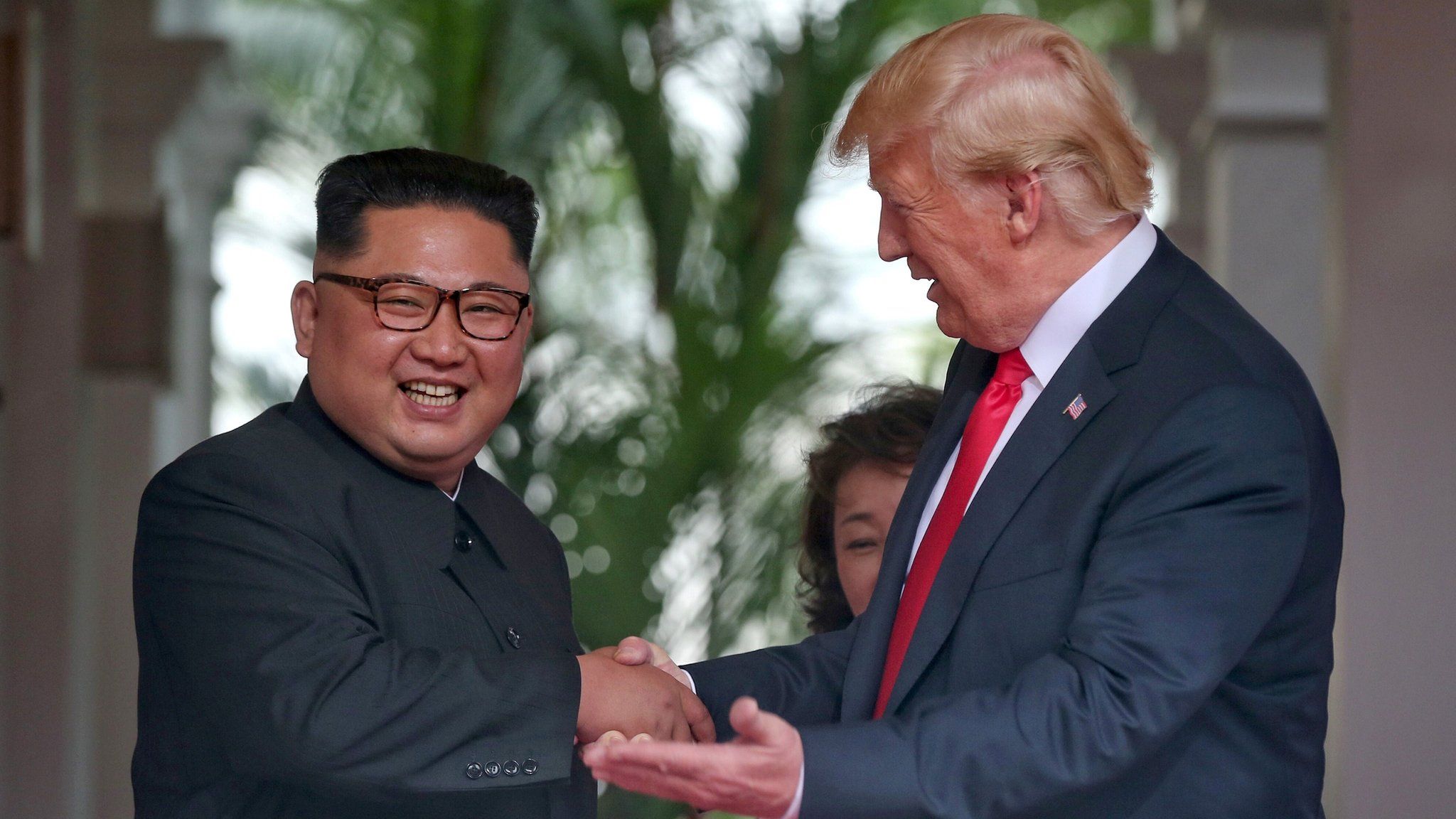 US President Donald Trump greets a smiling Kim Jong-un at the Capella Hotel on Sentosa island in Singapore