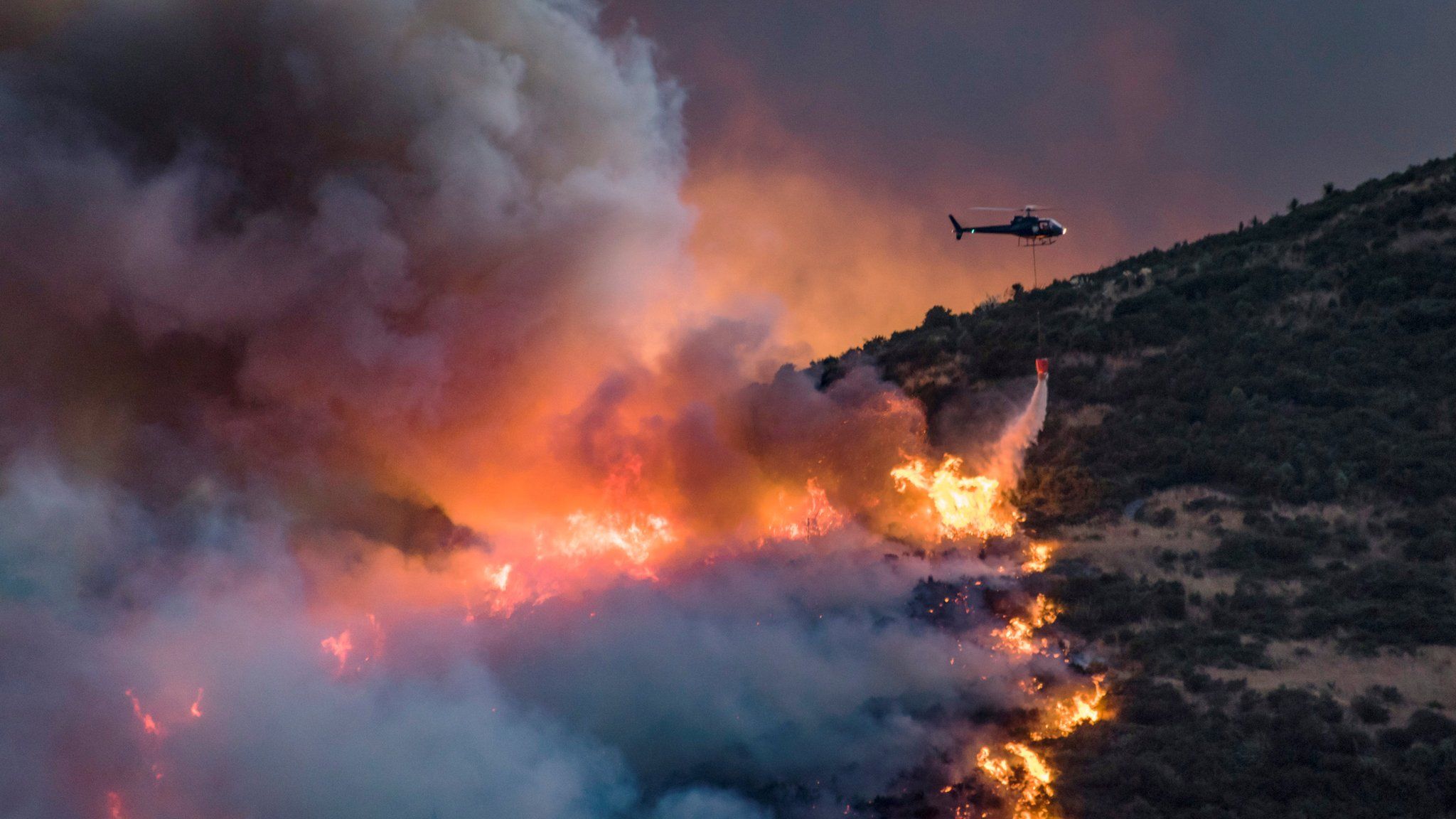A helicopter dumps fire retardant on wildfires near Christchurch on New Zealand's South Island, 13 February 2017