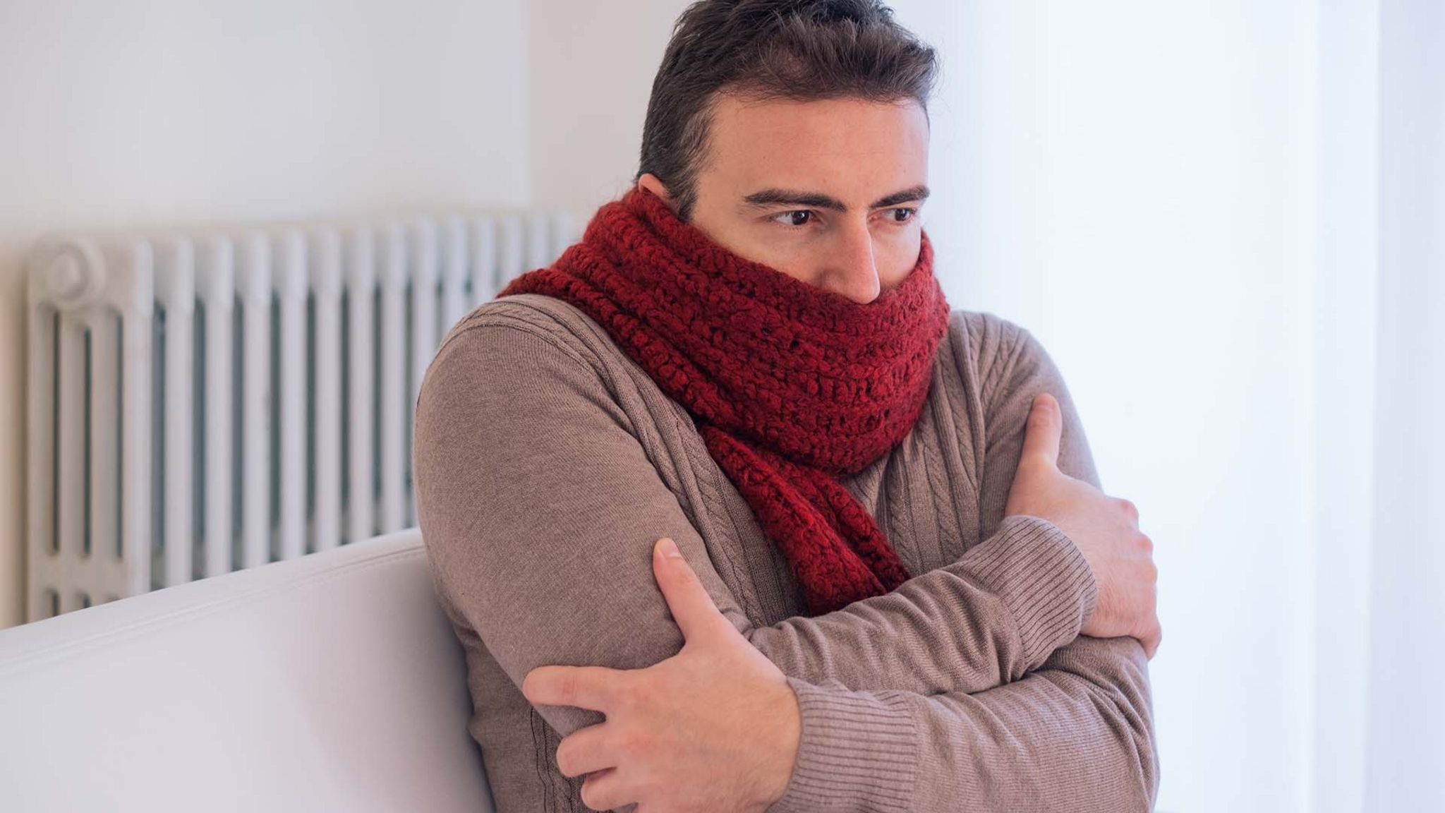 man shivering inside with scarf on