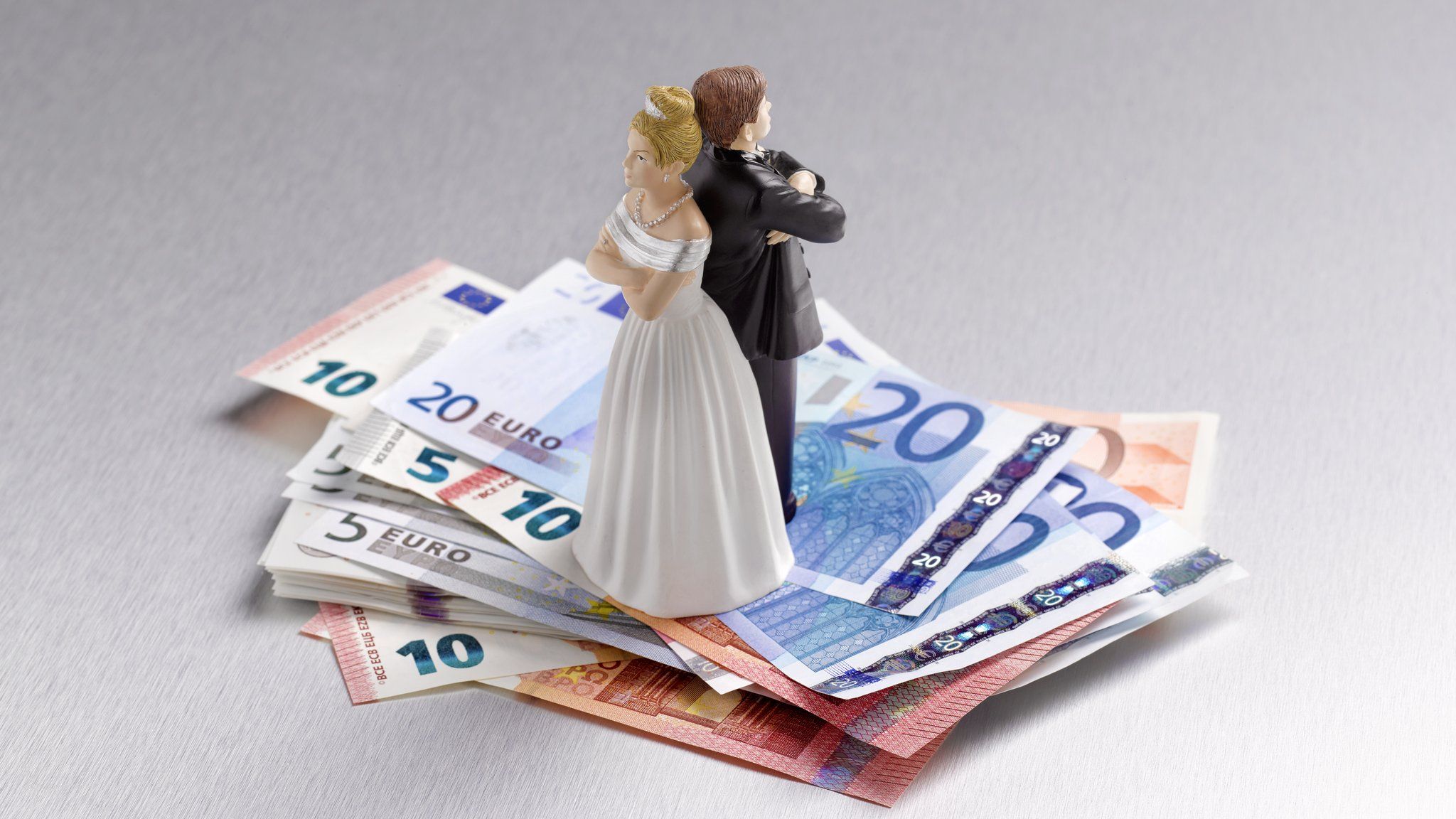 A model of a bride and groom standing on a pile of euros