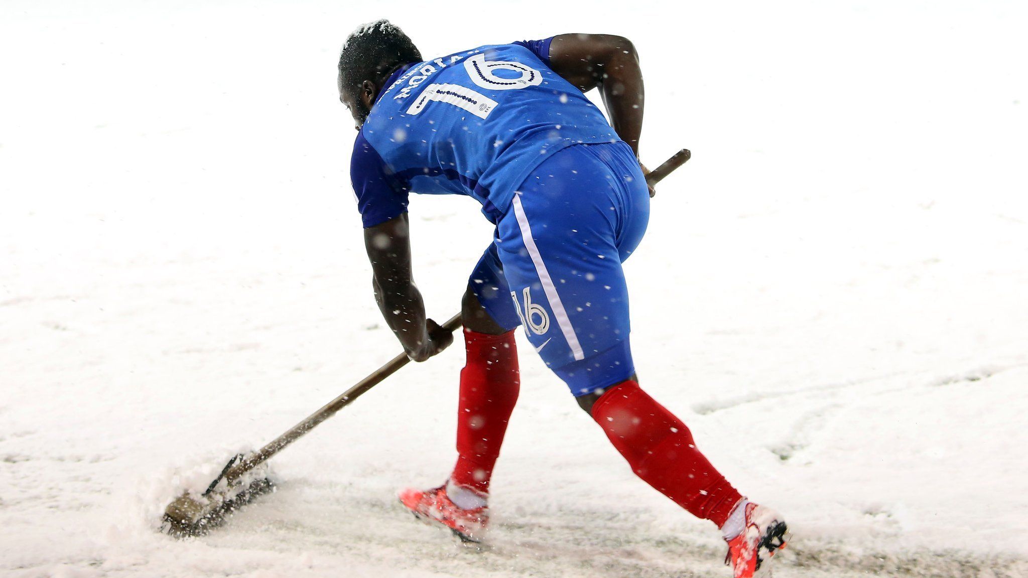 Peterborough United players help clear the lines in snow against Walsall