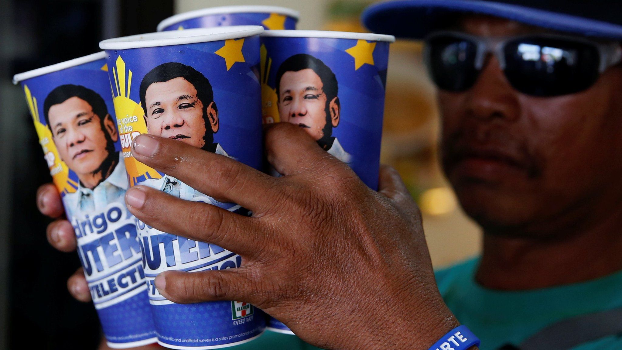 Four Duterte fizzy drink cups being held by a man out of shot