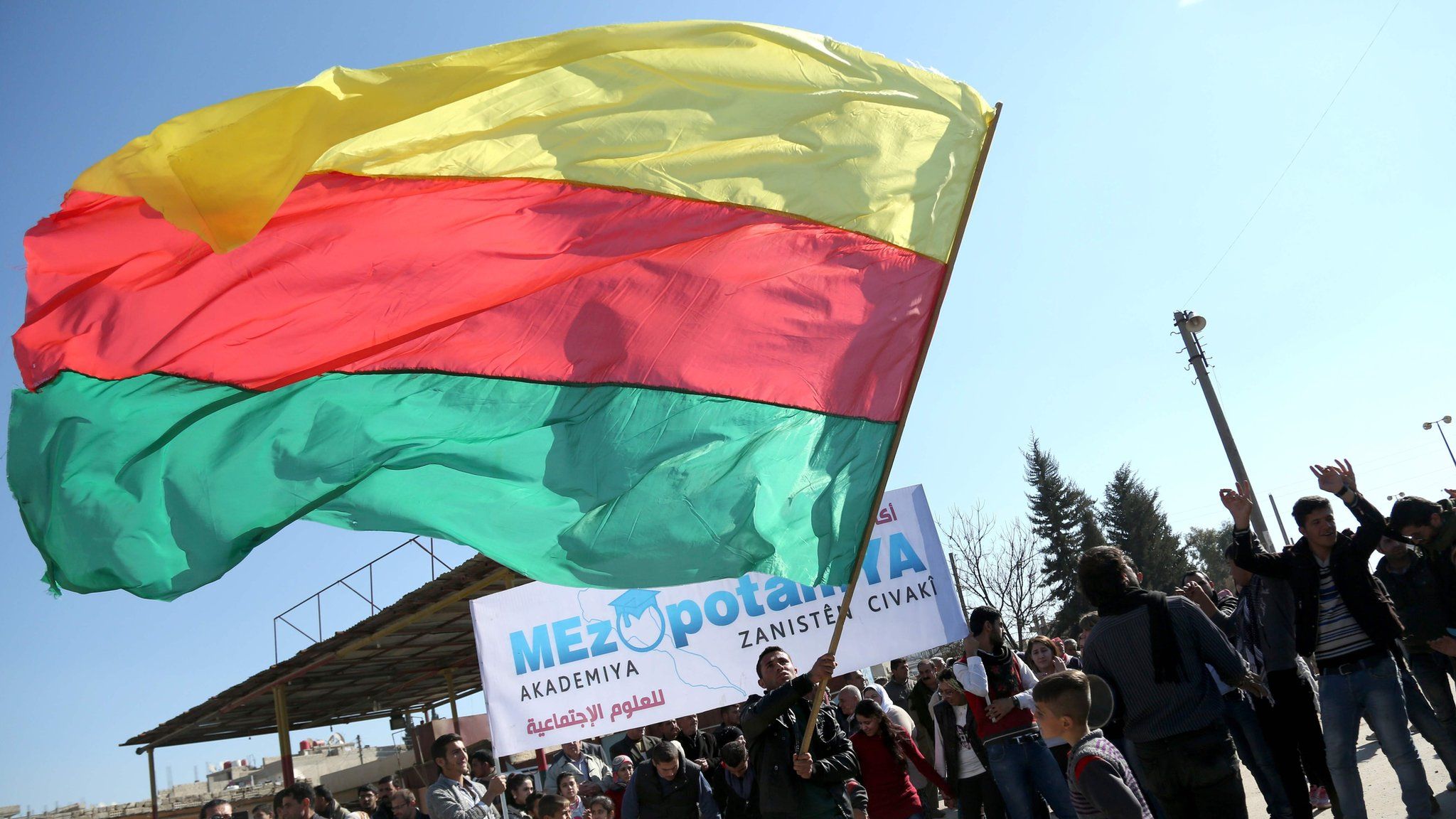 A Kurdish man waves the flag of the Kurdish Democratic Union Party (PYD) at a protest in Qamishli, Syria (4 February 2016)