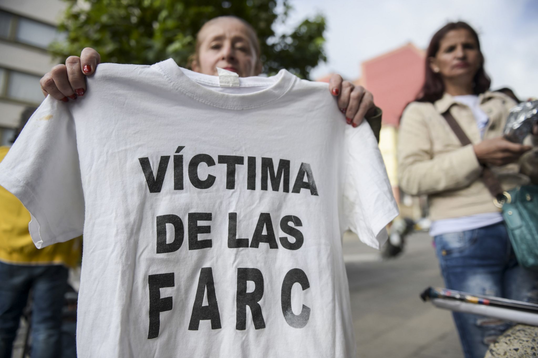 A woman holds up a T-shirt reading "Victim of the Farc" outsider the JEP in Bogota