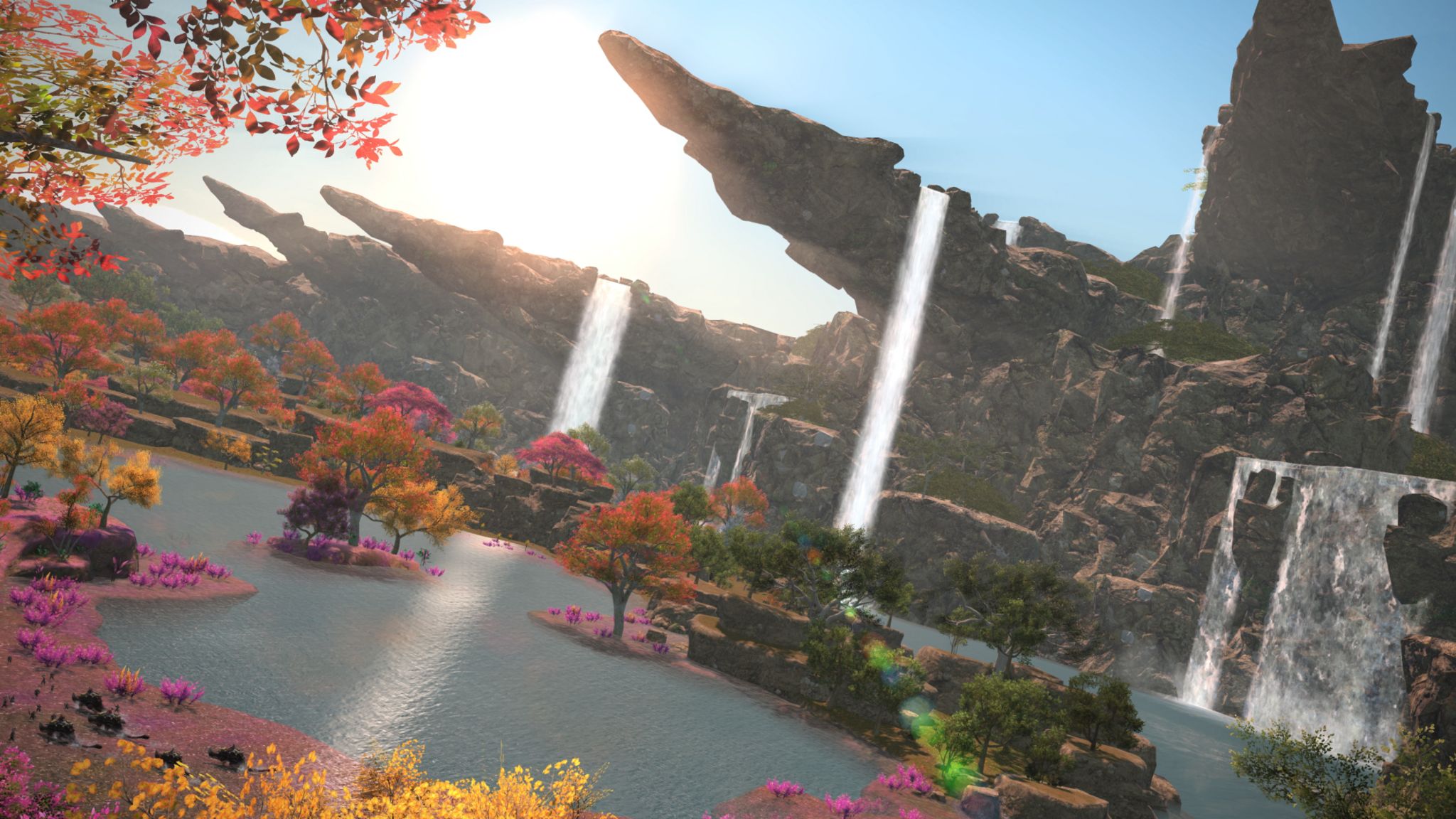 A still from Final Fantasy showing colourful trees, a waterfall and blue water, with high rocks and hills.
