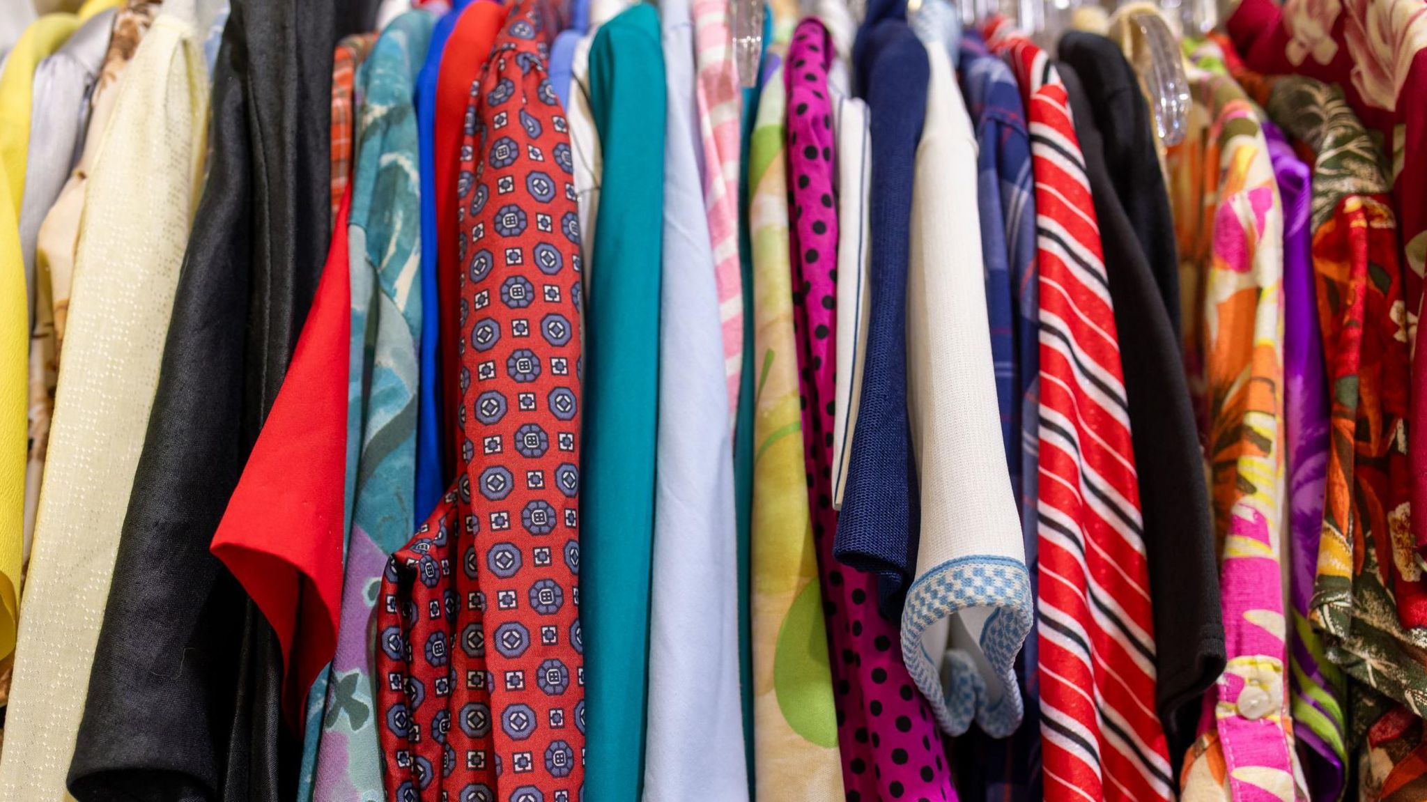 An up-close rack of colourful shirts displayed in a shop. 