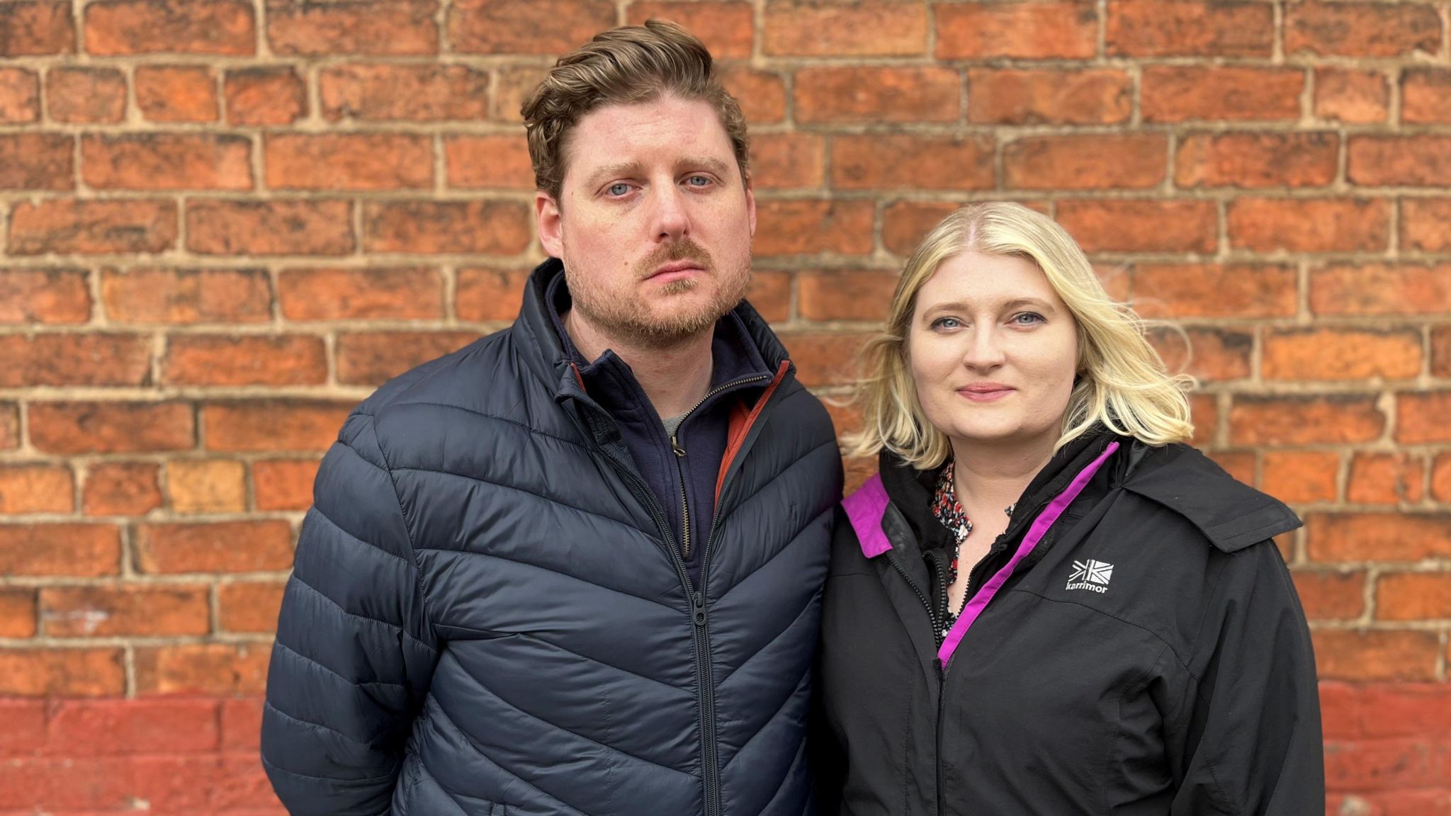 Thomas and Katie Watson stood in front of a brick wall