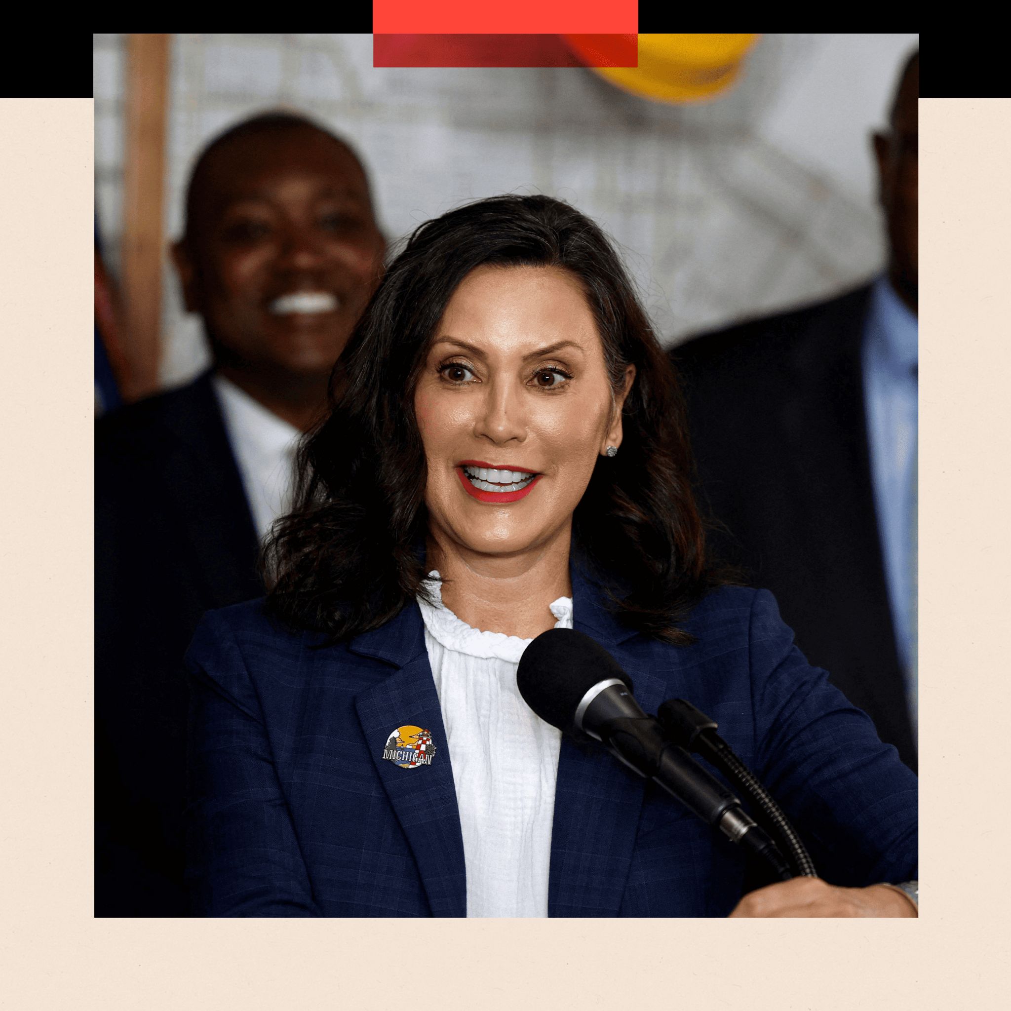 Gretchen Whitmer speaks into a microphone. She is wearing a white short and a navy blue jacket