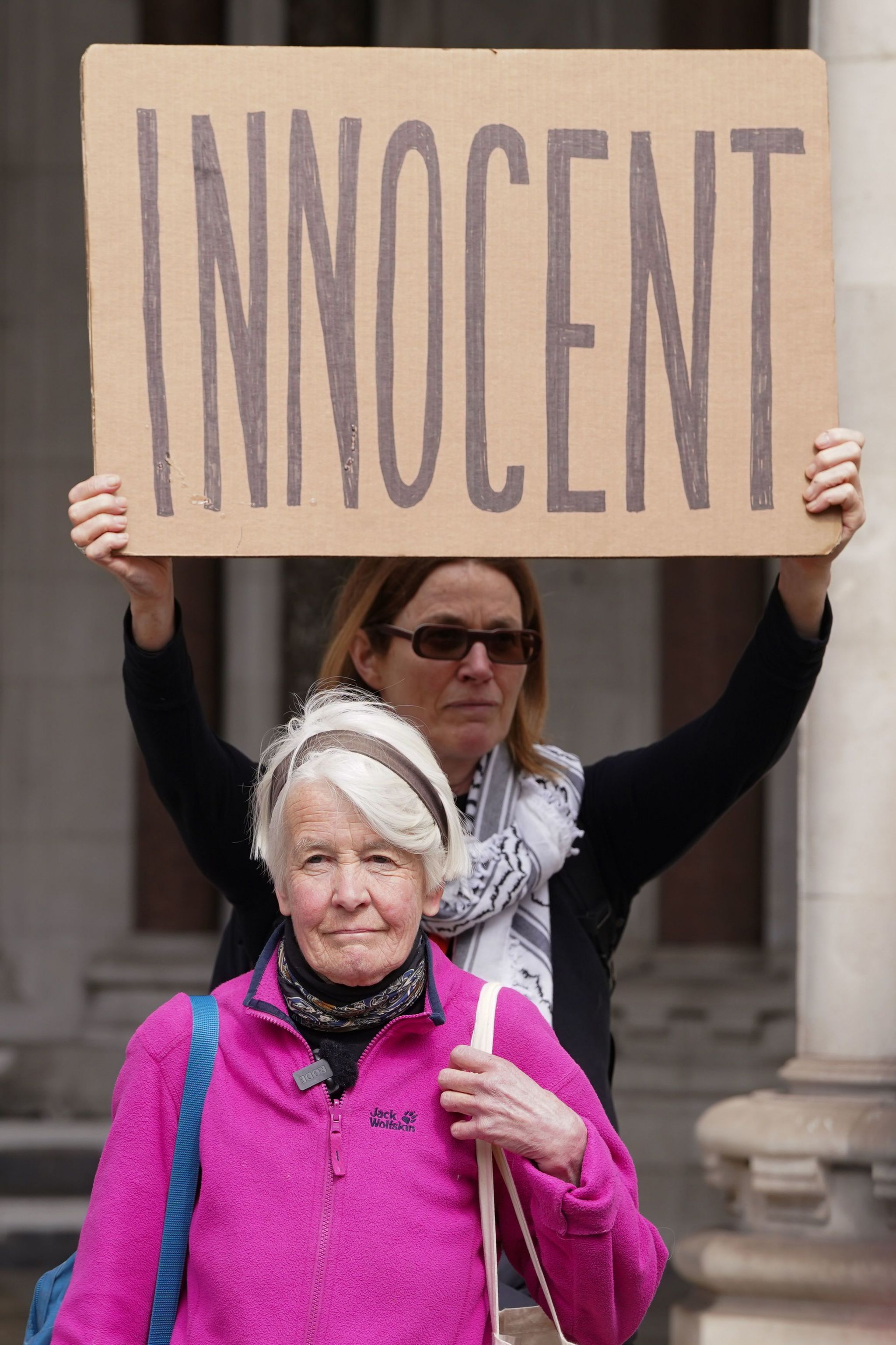 Trudi Warner outside the Royal Courts of Justice in London with an 'innocent' sign behind her