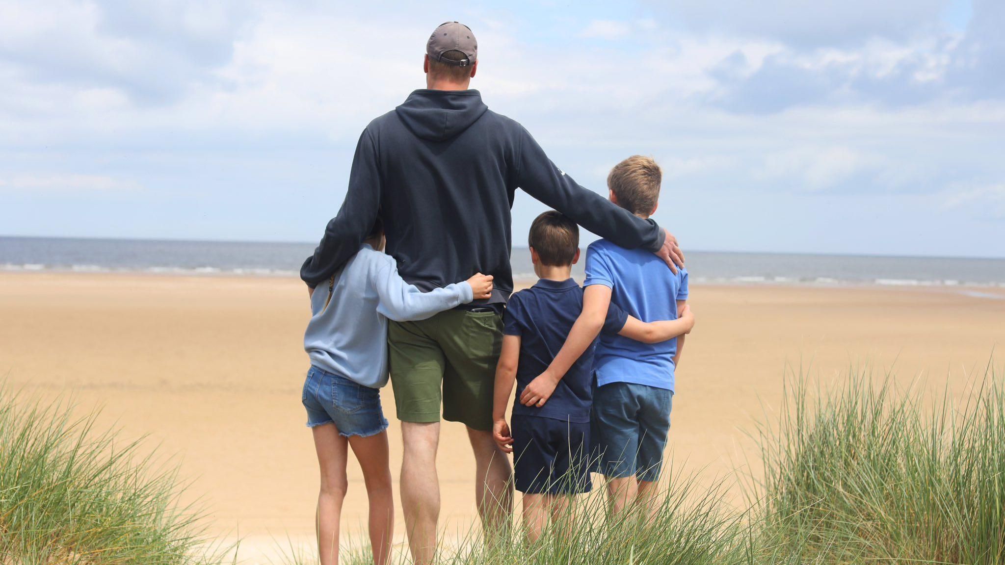 William and children on a beach looking out to sea