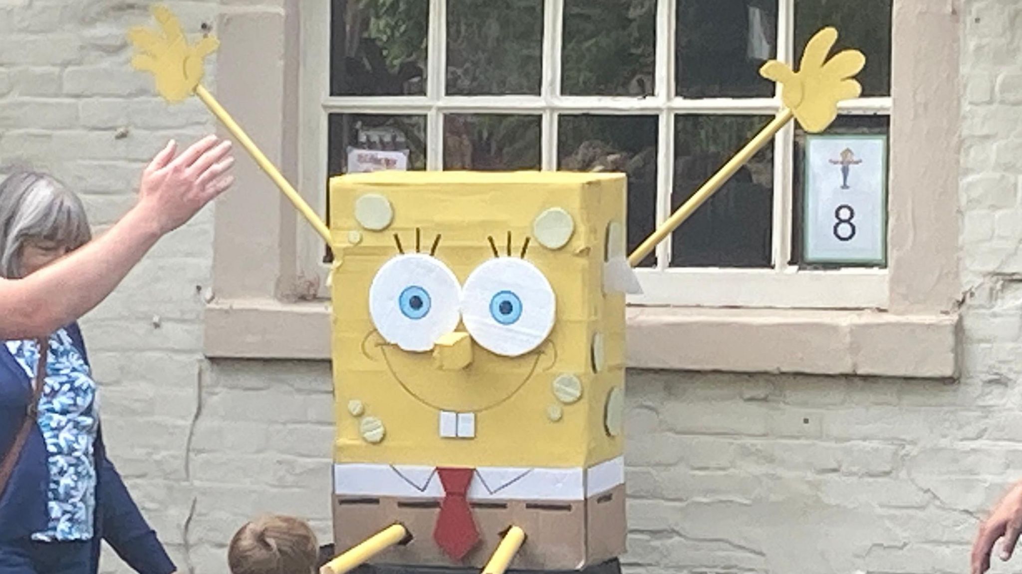 A cardboard lookalike of Spongebob Squarepants in front of a window