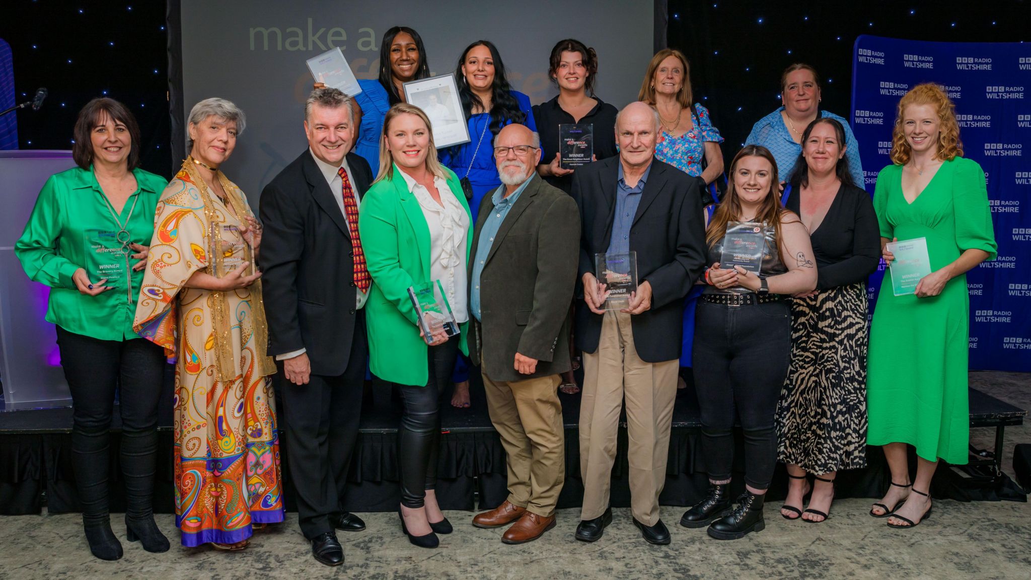 Award winners holding their awards at the stage