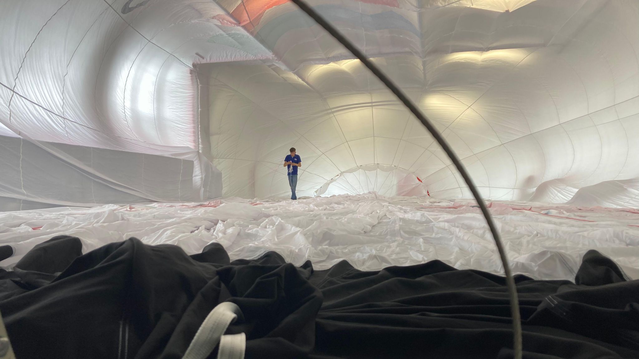 A man walking through a balloon which has air blowing through it.