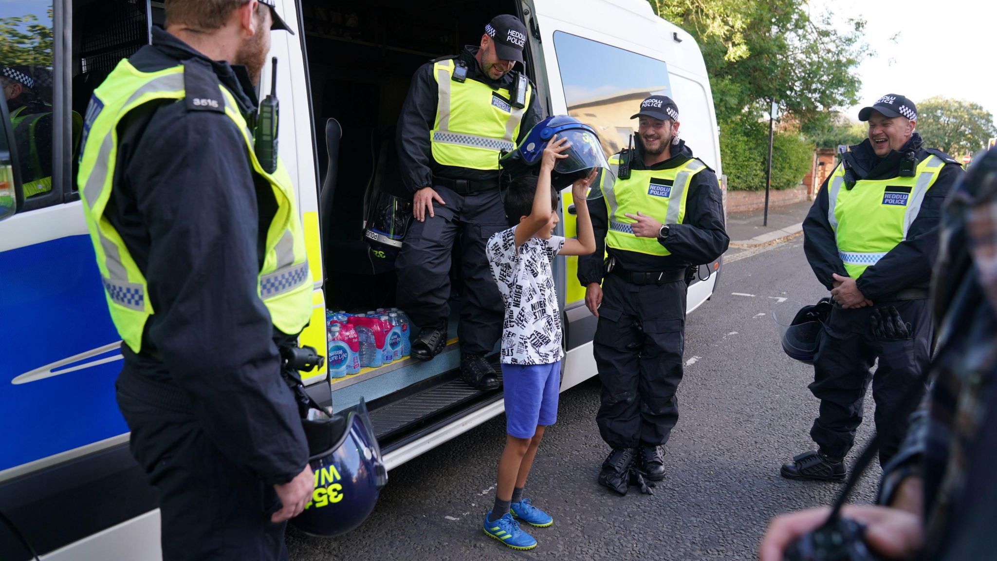 Nine-year-old Hassan Boston Khan tried on a police officer's helmet after giving them water ahead of an anti-immigration protest in Newcastle