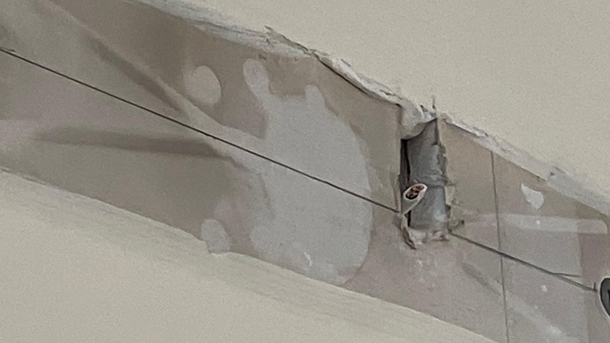 A gap in plaster shows a cut wire sticking out