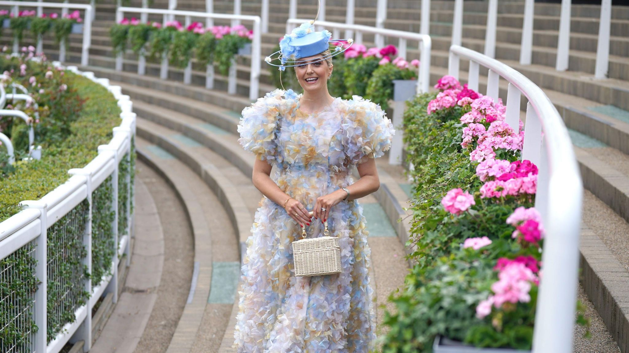 Charly Blackburn wears a ruffled short sleeved, long floral light blue dress and pale blue hat