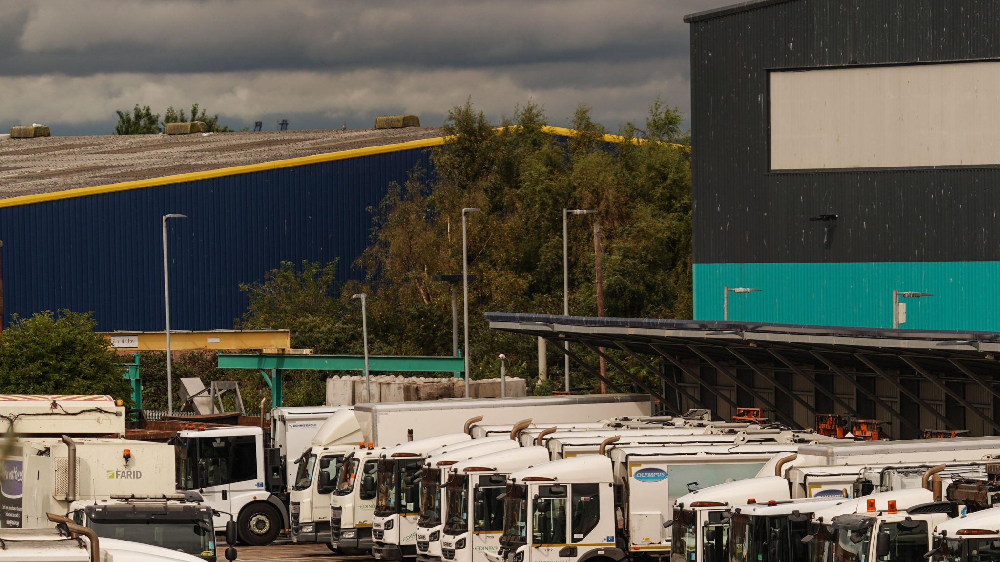 White bin lorries lined up at a car park of a waste depot centre