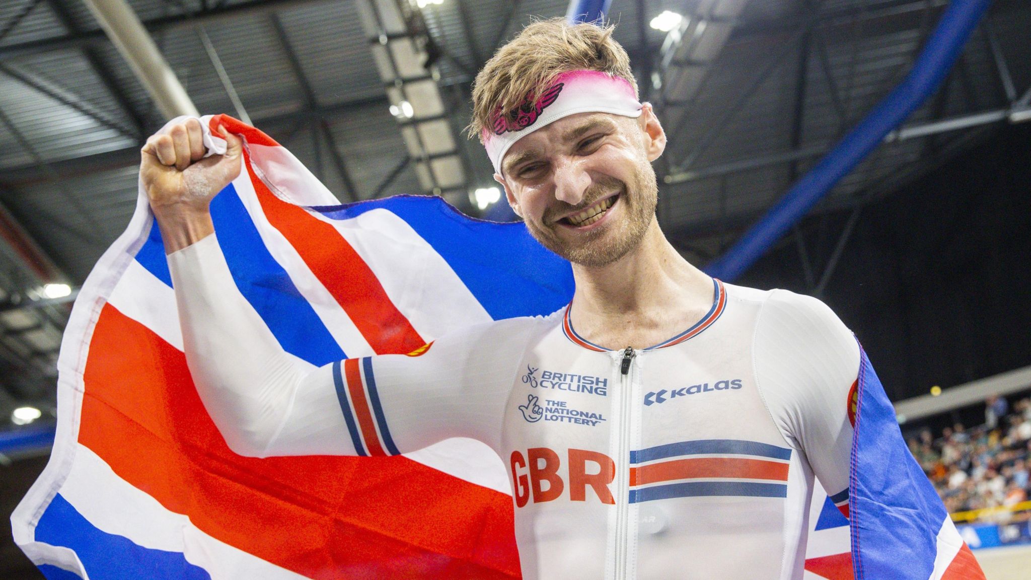 Dan Bigham holds the Union Jack after winning the individual pursuit at the European Track Cycling Championships in 2024