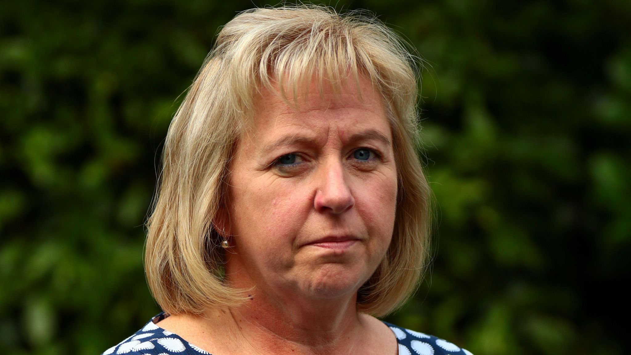 Catherine O'Sullivan, who has blonde hair, looks at the camera with a sombre expression.