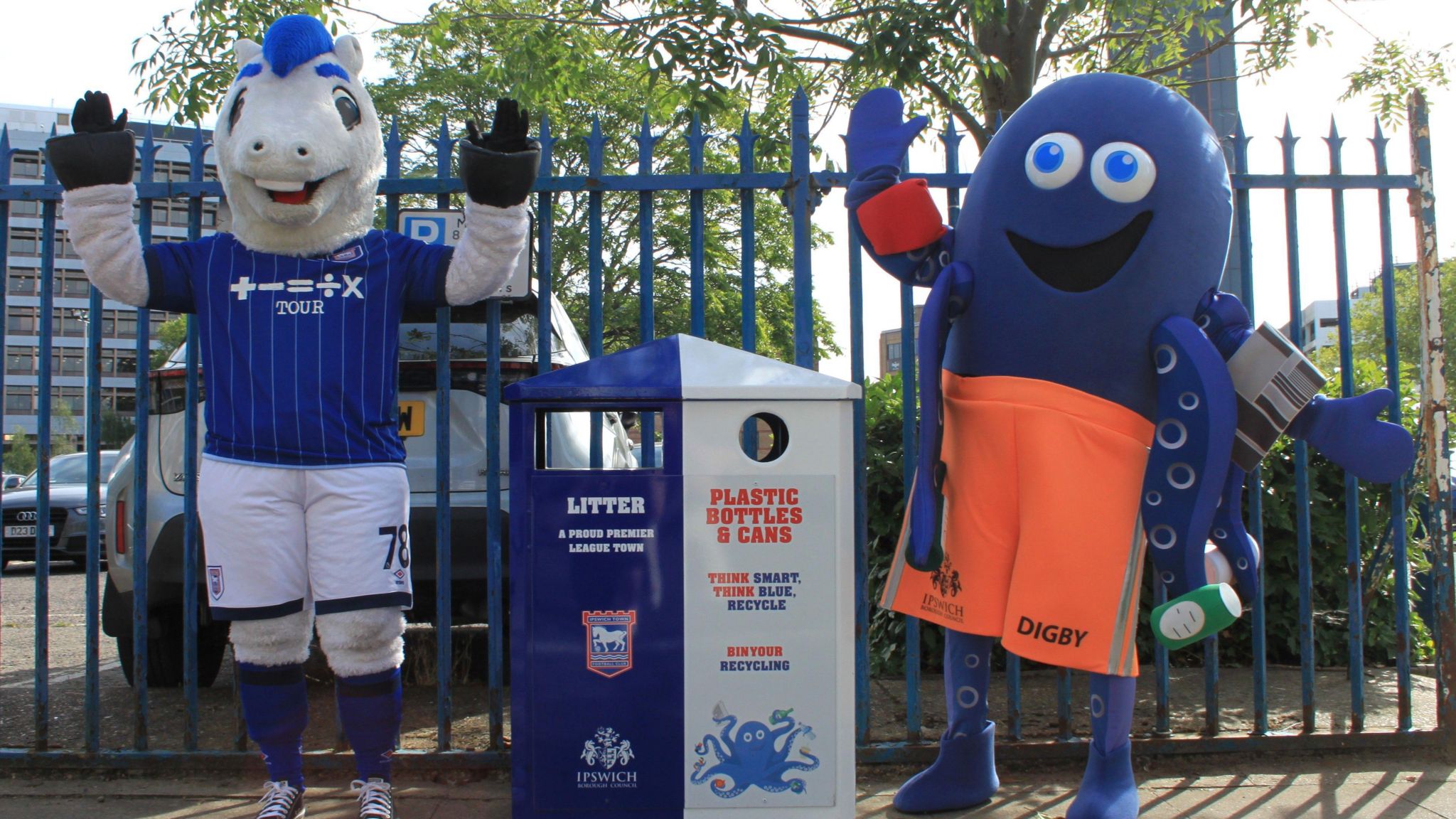 Ipswich Town mascot Bluey standing next to the new blue and white recycling bins