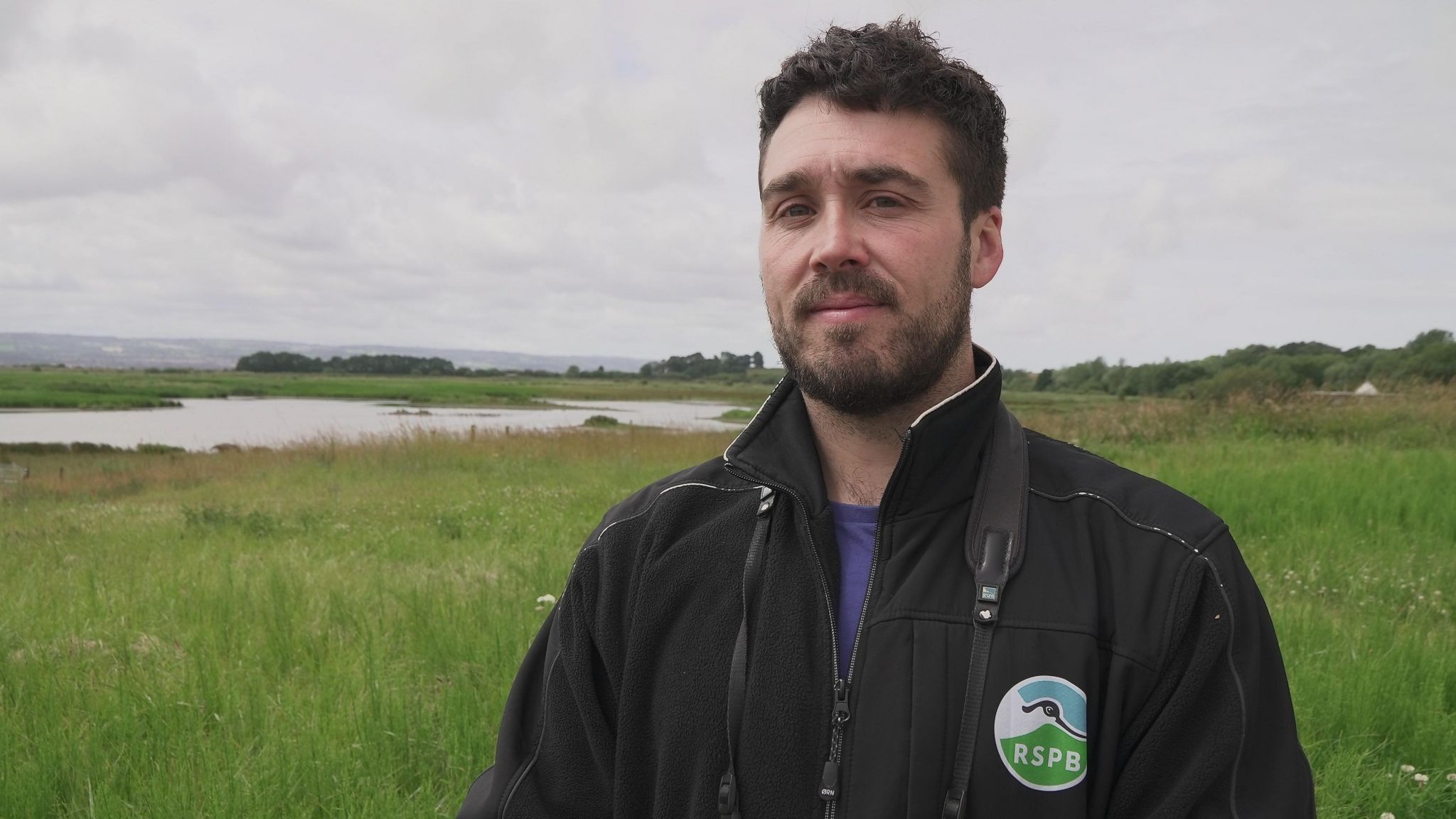 Dan Trotman wearing an RSPB jacket on the marshland