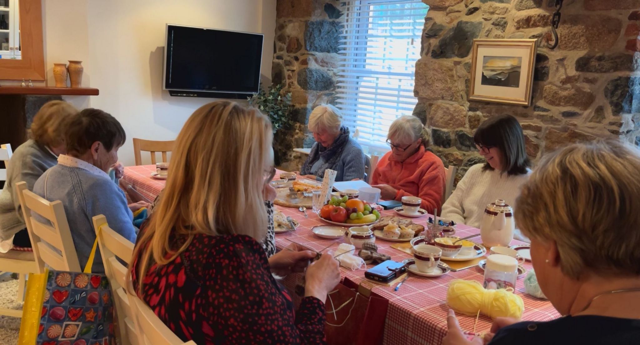 Women sat around a dining room table knitting