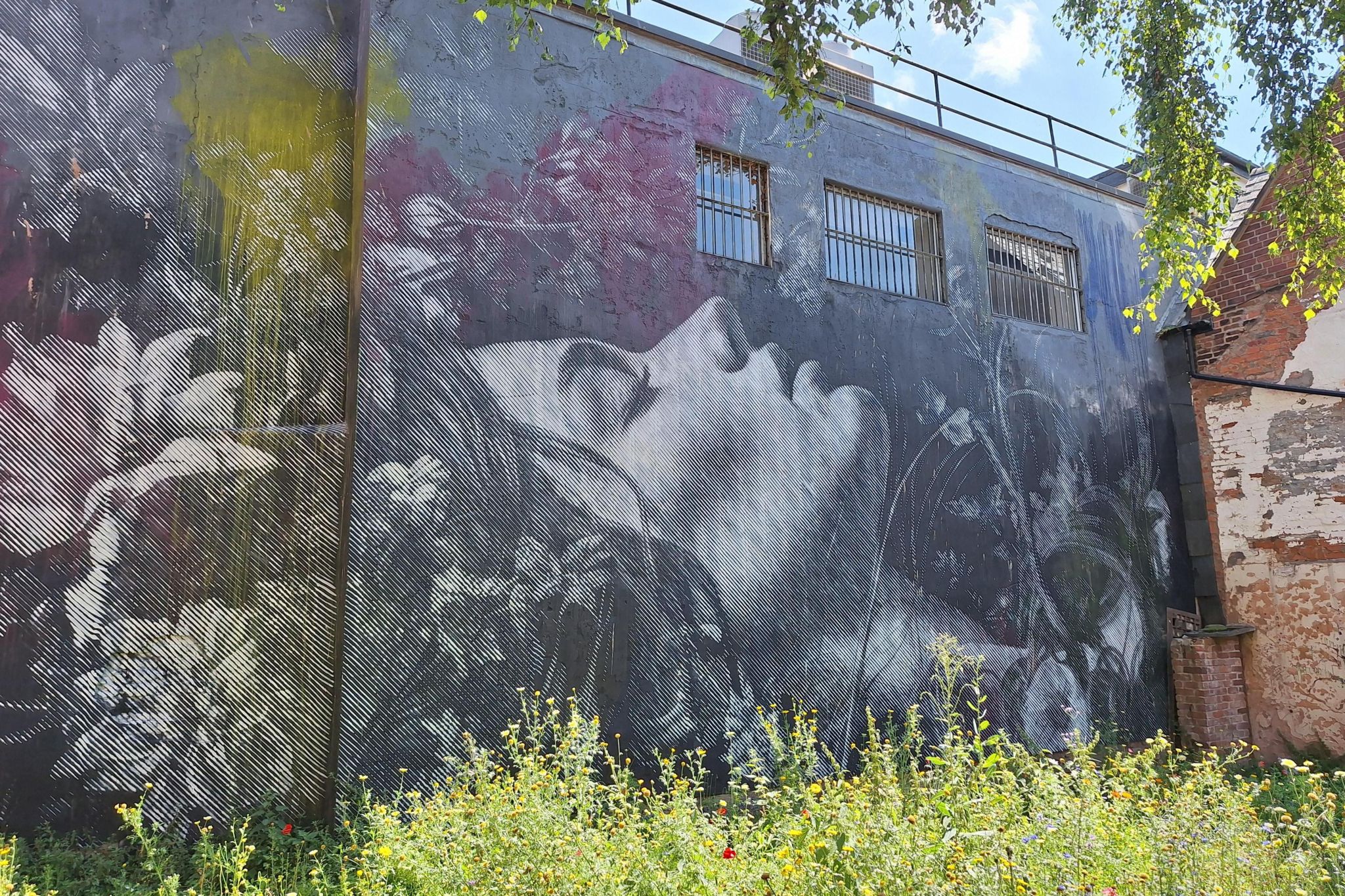 An almost-photographic mural on a building wall, showing a woman with flowers in her hair apparantly sleeping. 