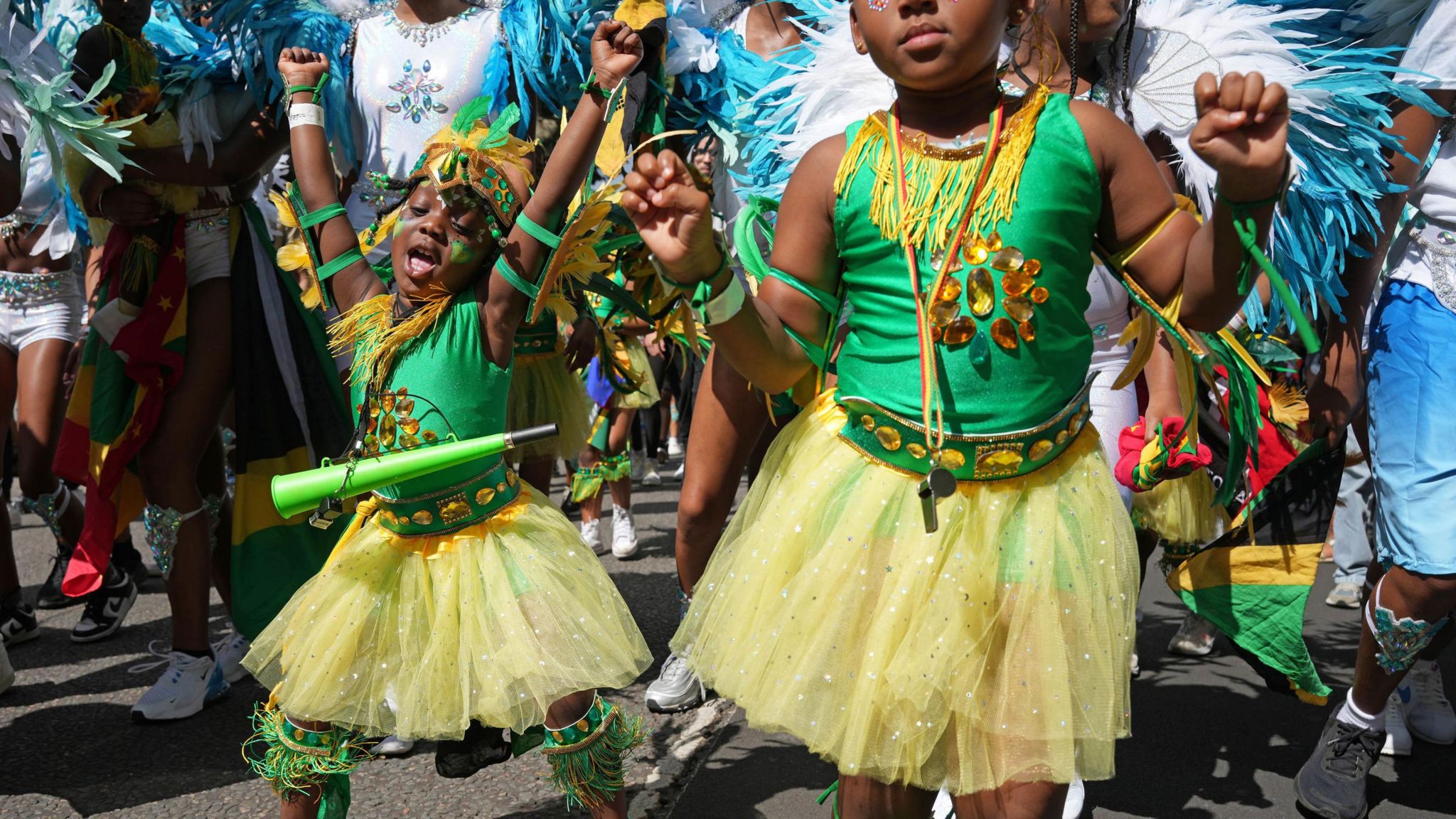 Two girls dancing in yellow tutu skirts and green vest tops